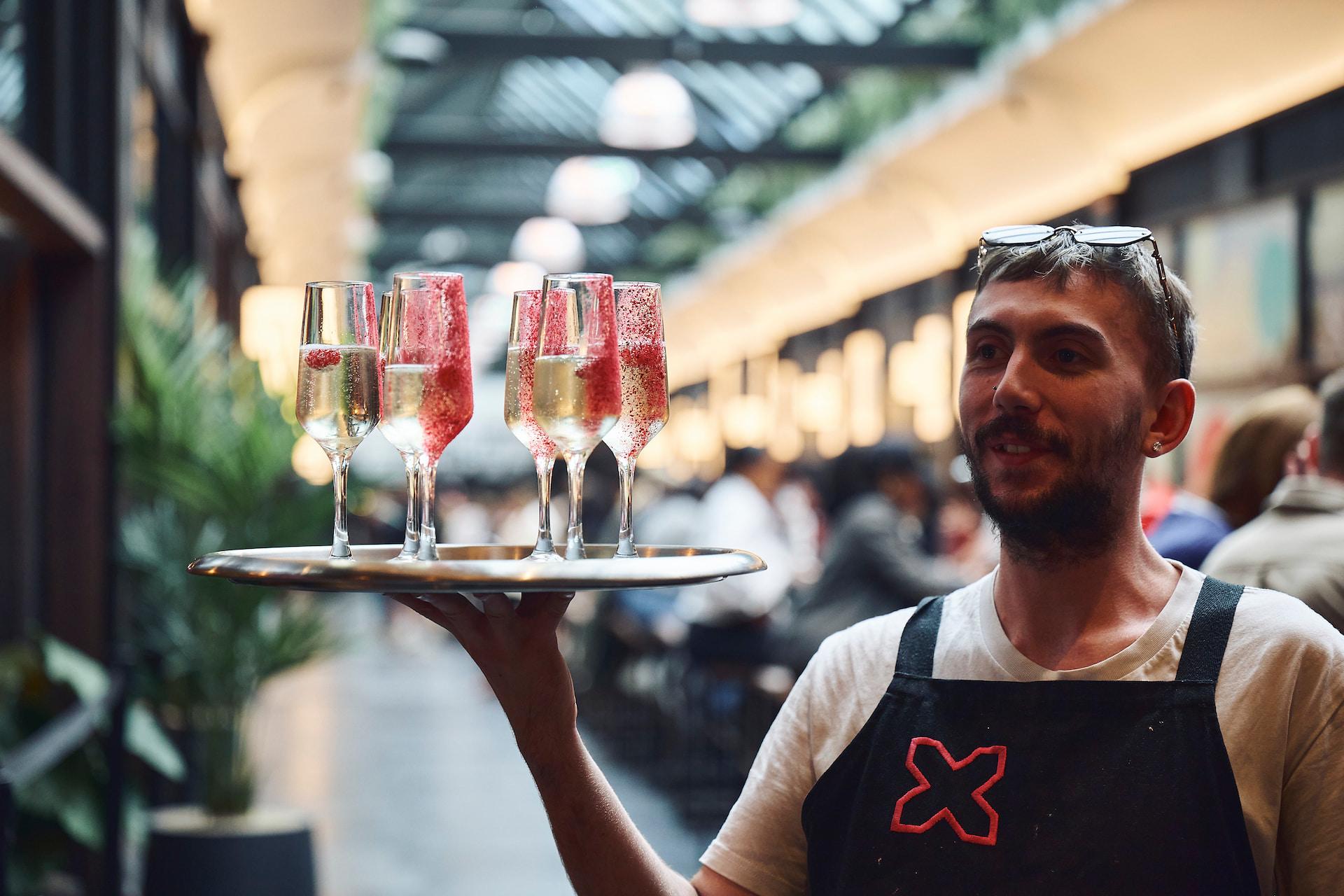 A waiter holding a tray of prosecco at BOXHALL in Liverpool Street