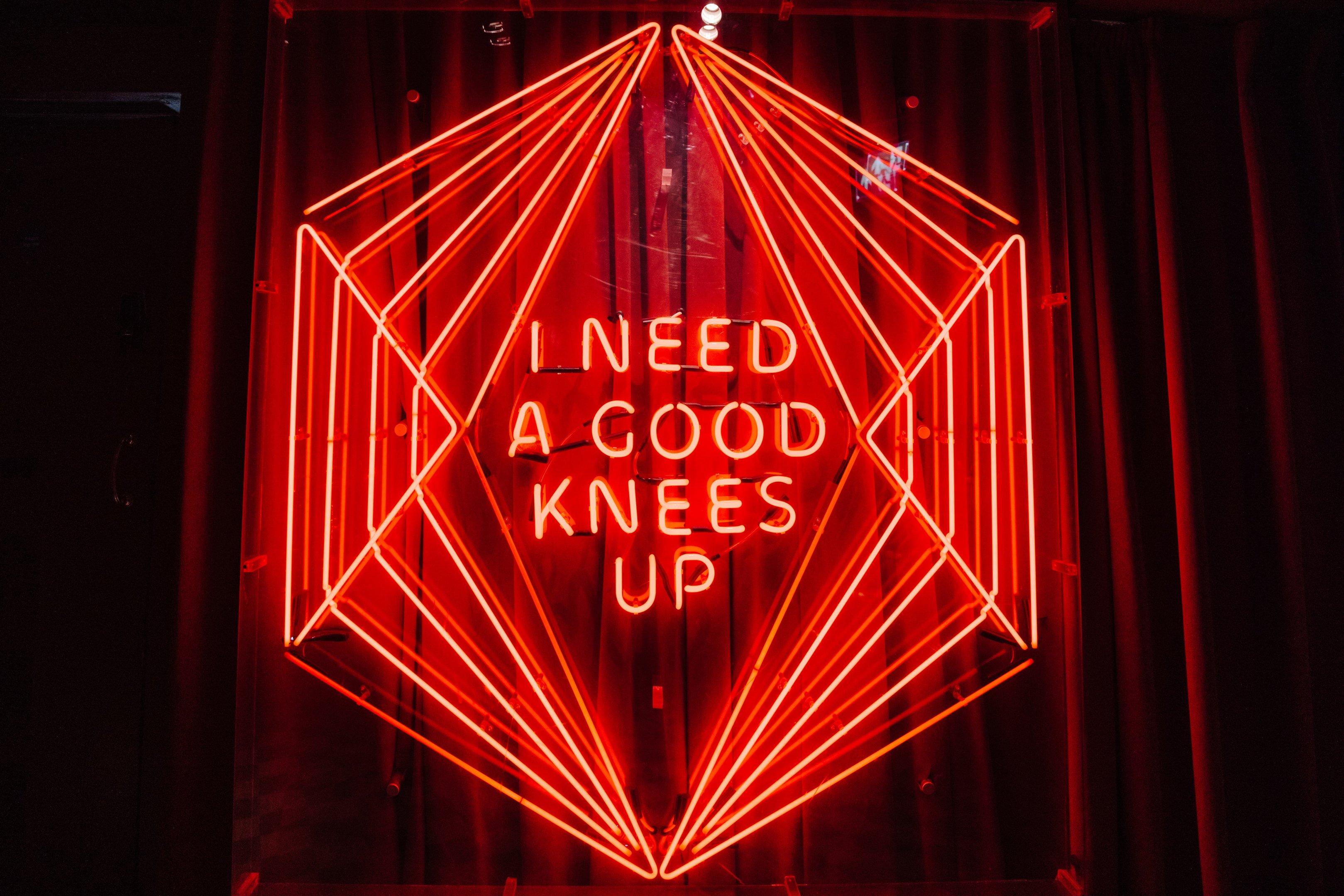 Neon sign saying I need a good knees up