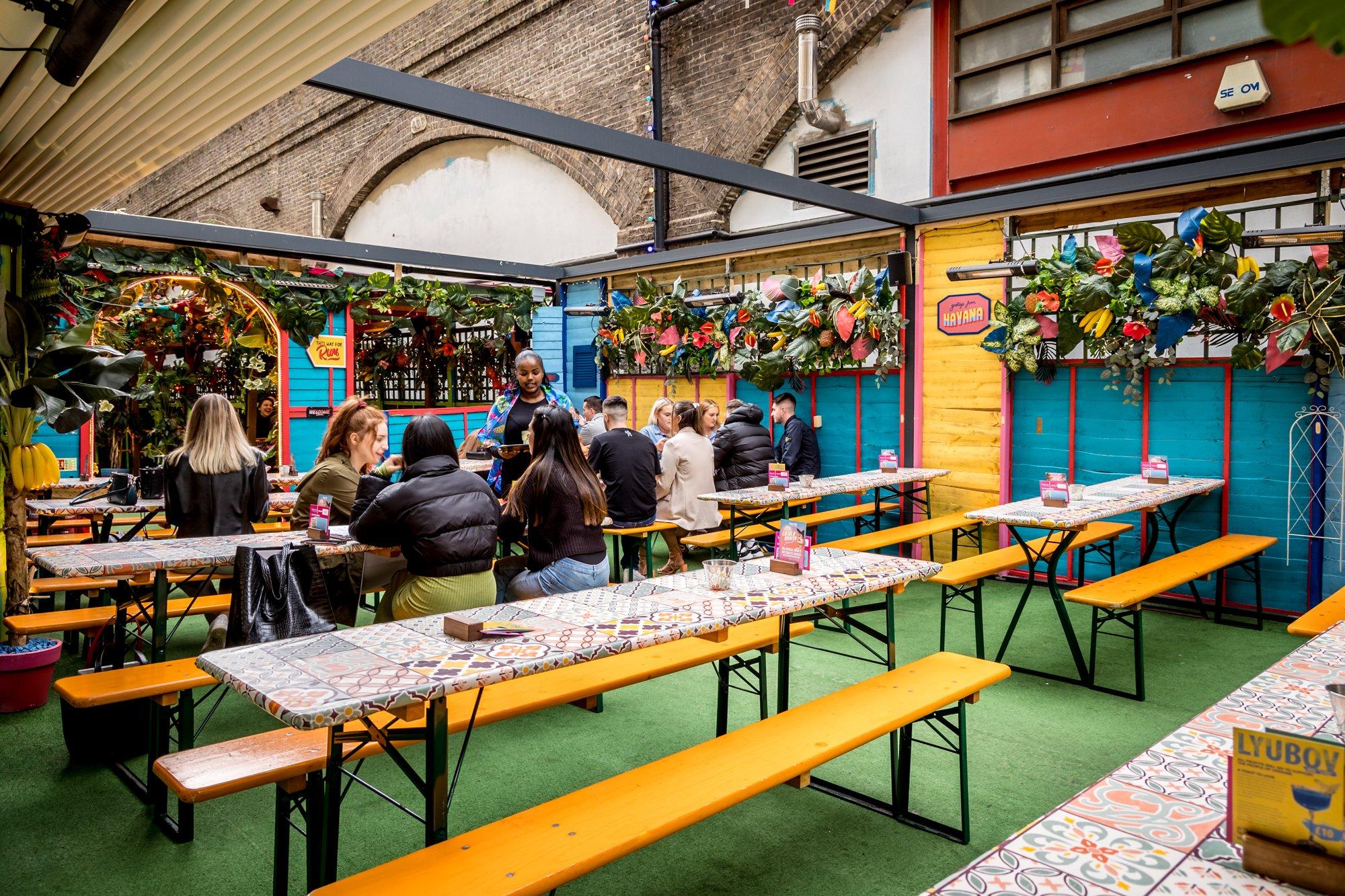 Colourful outdoor seating area with long tables and benches in Barrio, Shoreditch