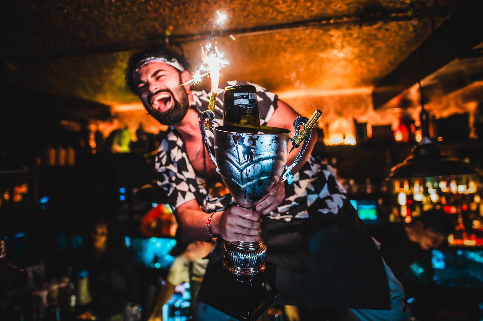 Bartender holding a cocktail sharer in the shape of a trophy