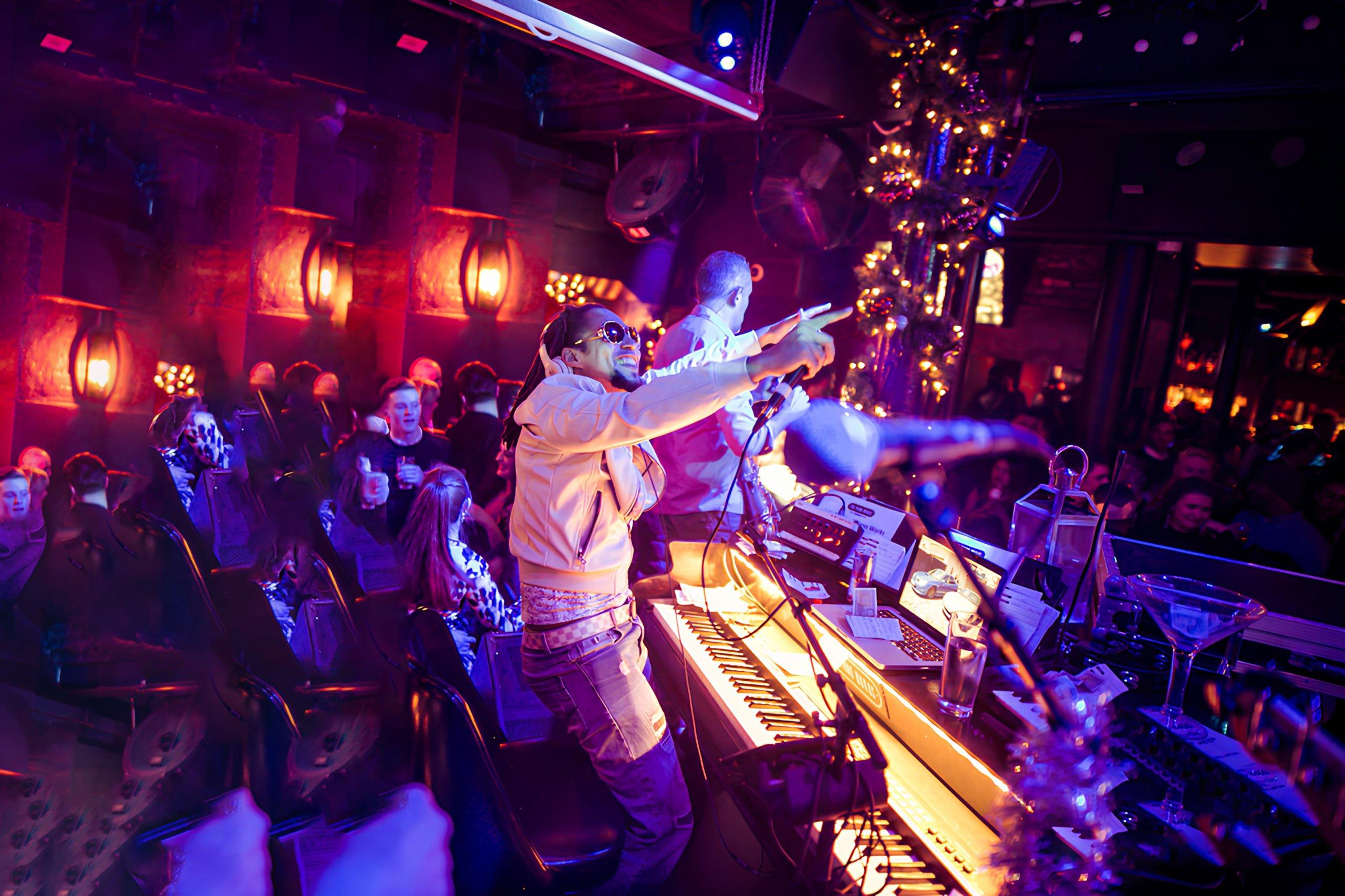 Pianist standing up next to his piano at The Piano Works bar in London