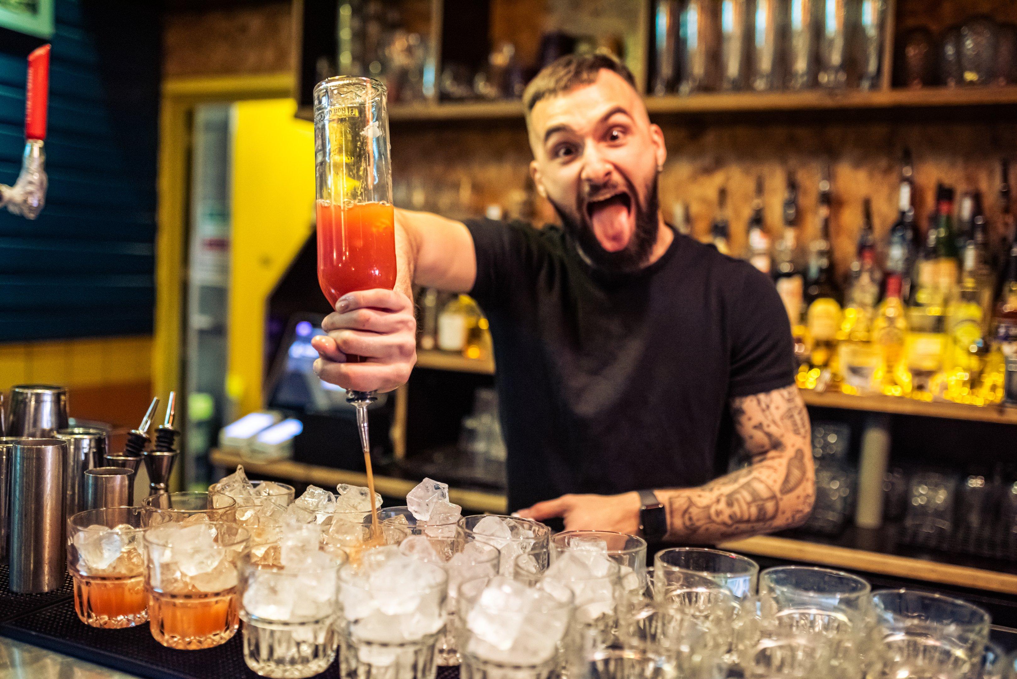 Bartender pouring drinks behind a bar in Barrio