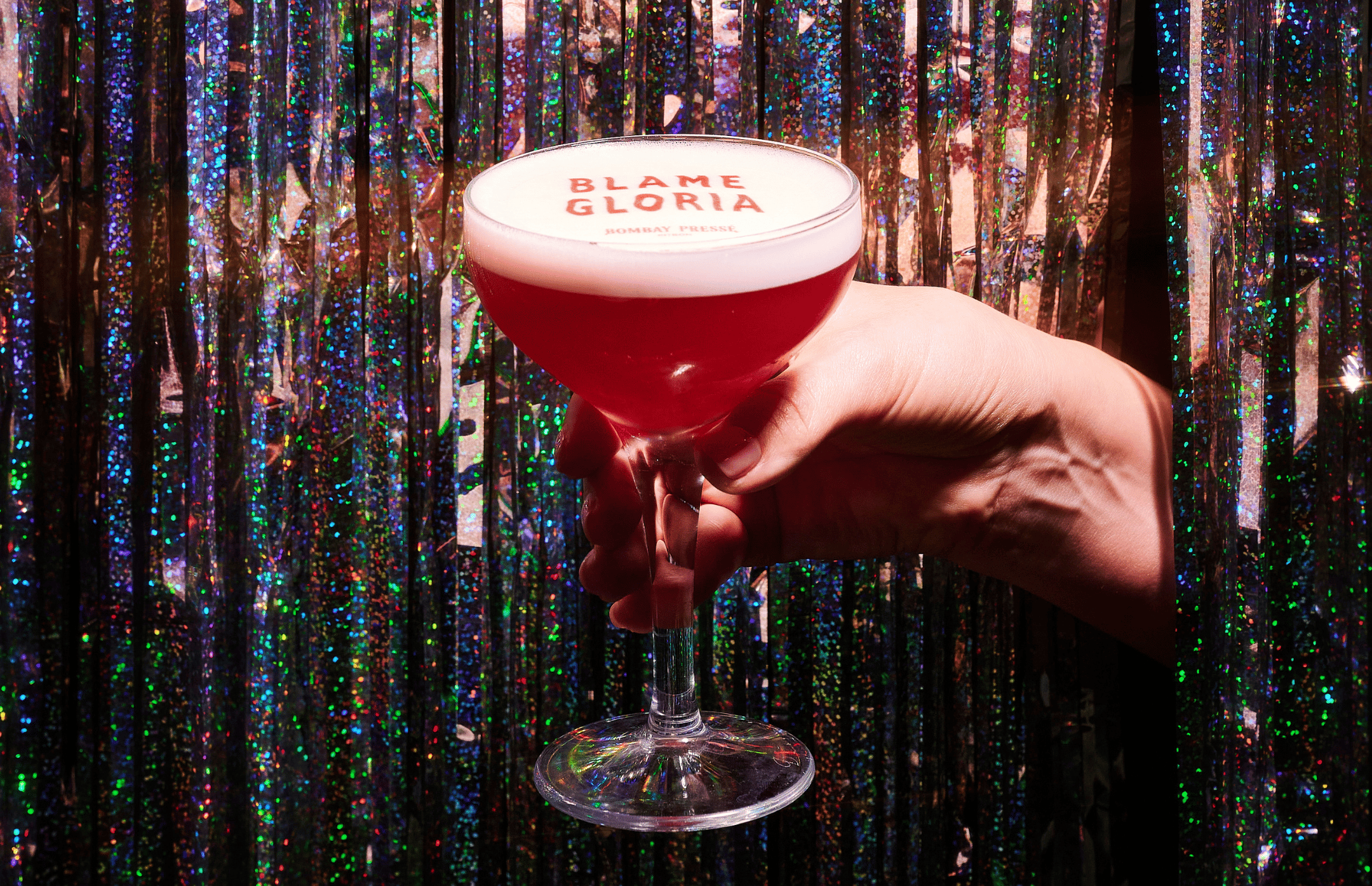 A festive cocktail in front of a glitter curtain in Blame Gloria cocktail bar