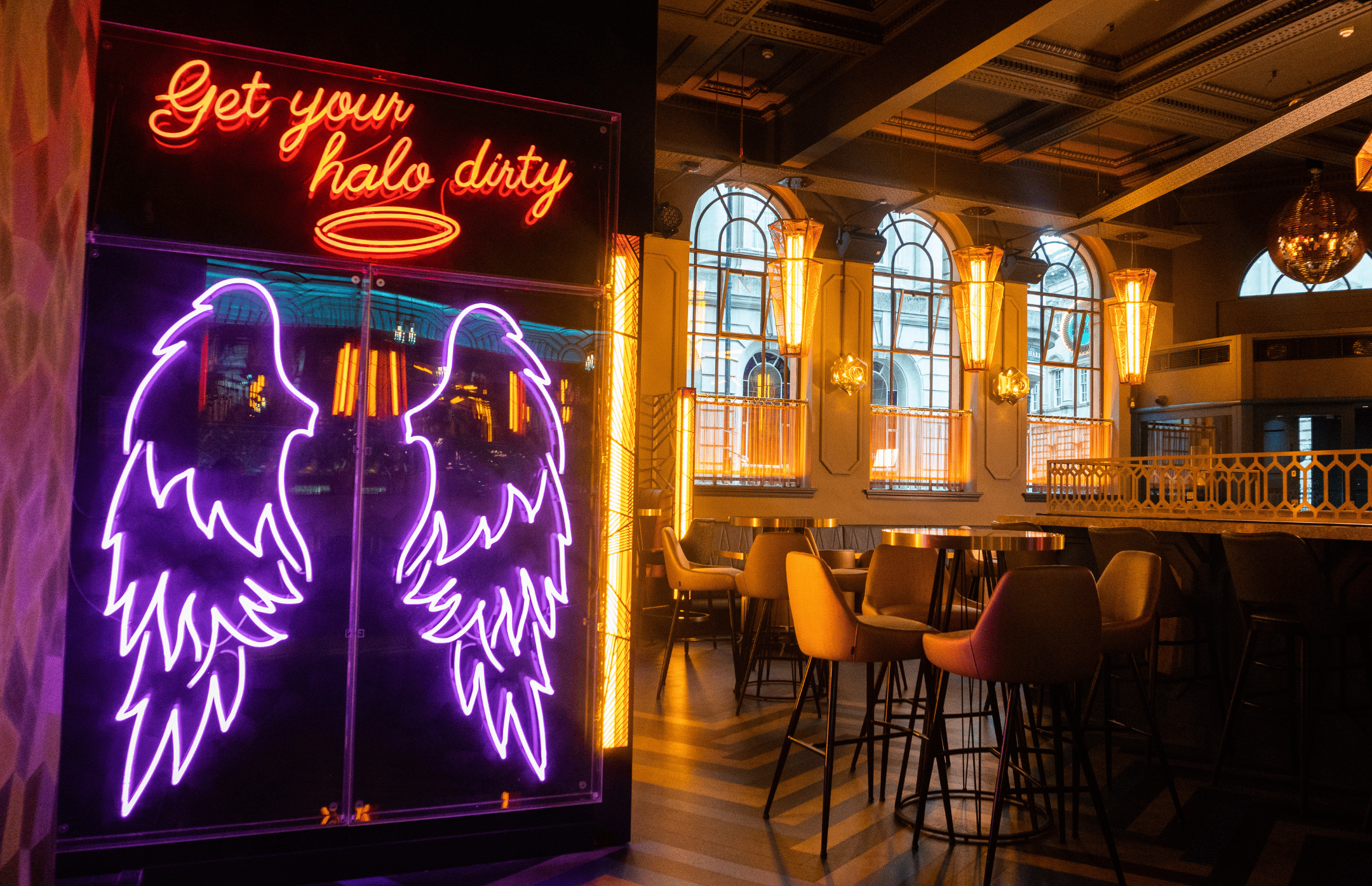 Neon angel wings sign and seating area in Dirty Martini Bristol