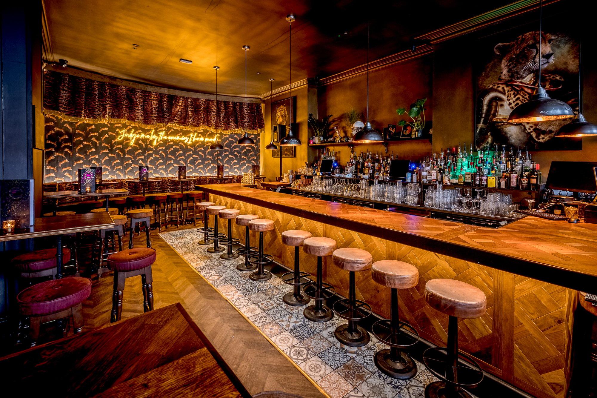 A golden bar area with leopard wallpaper and stool seating