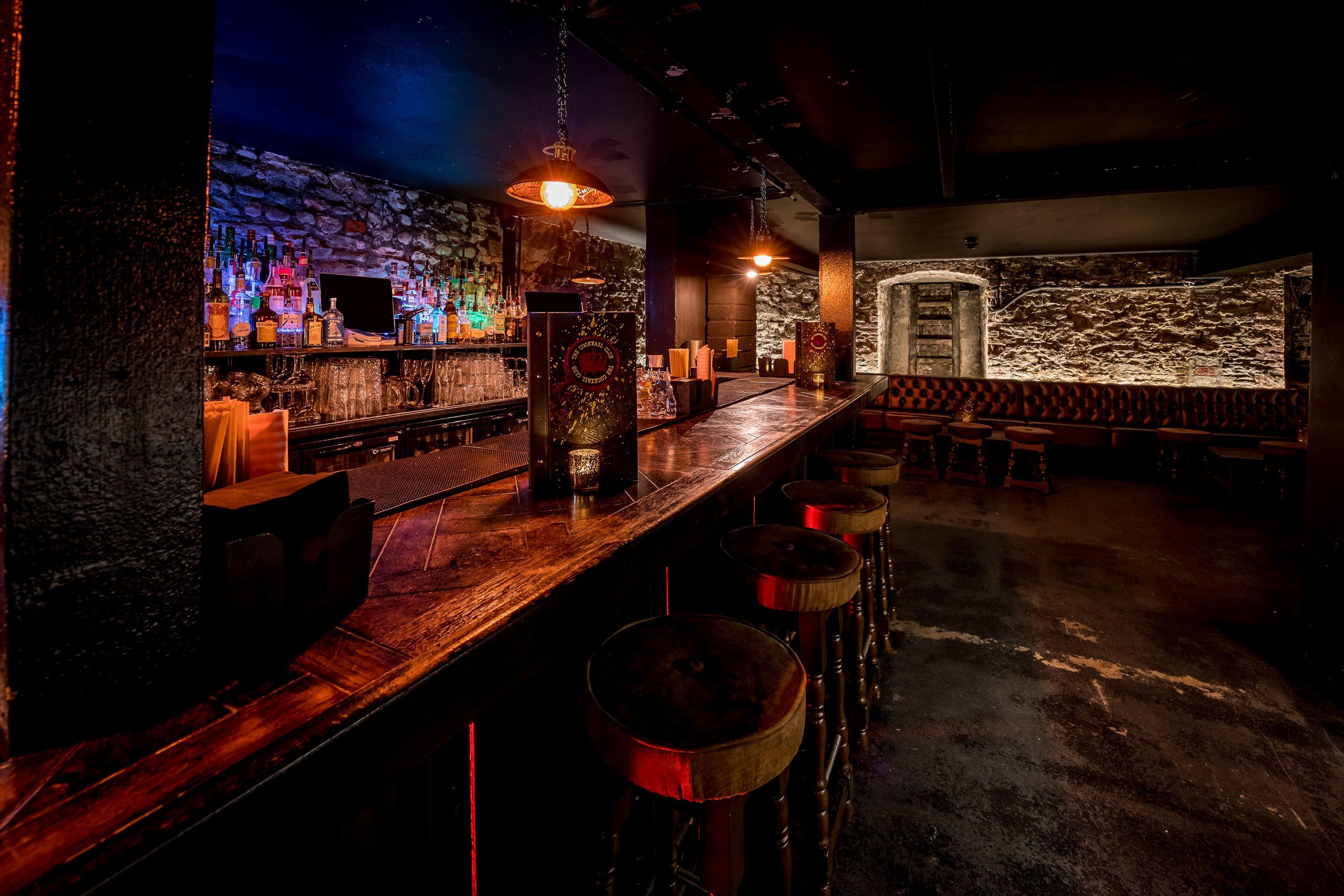 A basement bar area with exposed brick walls and moody lighting