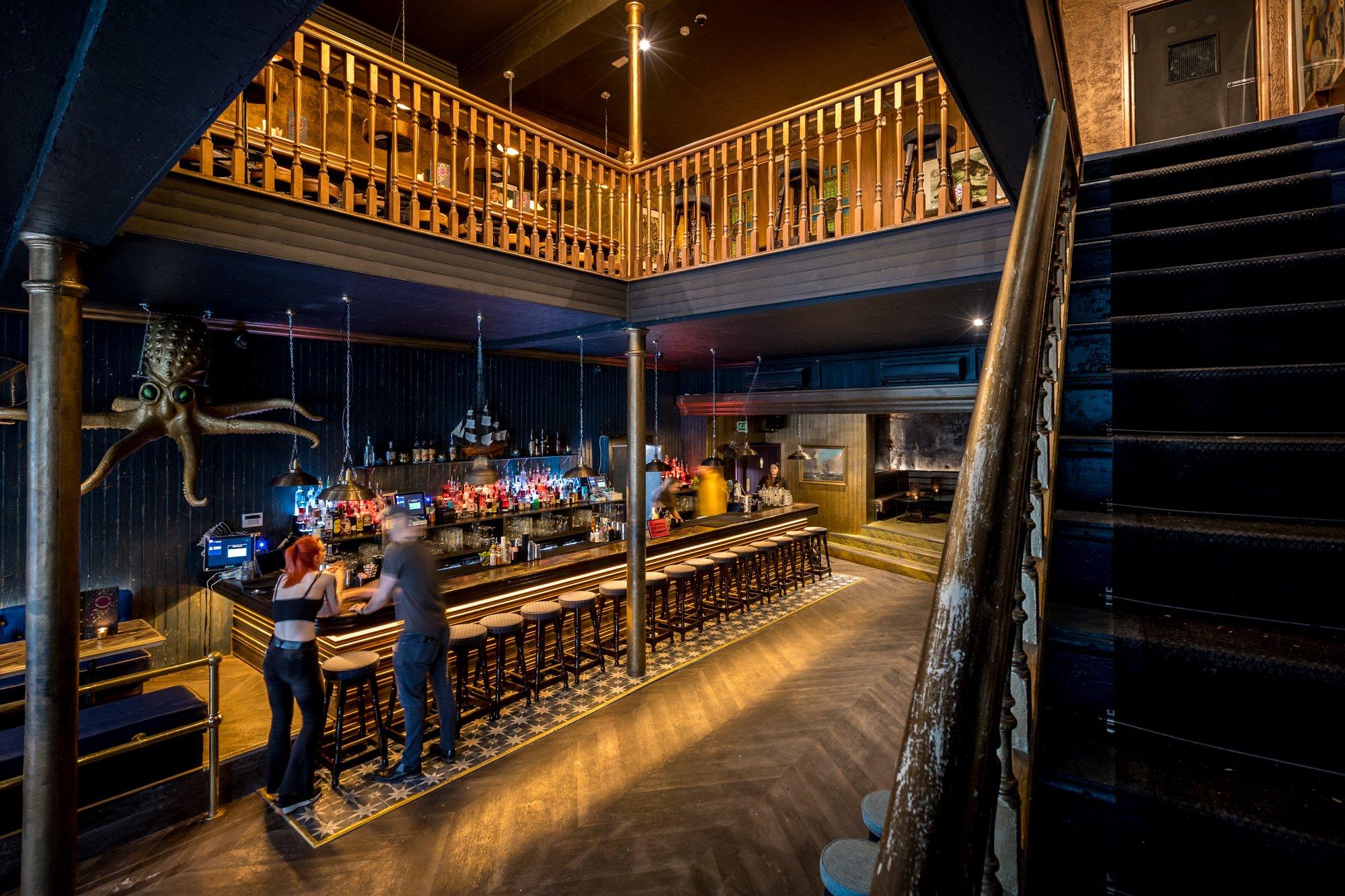 A blue and golden bar with stairs leading to the upstairs bar