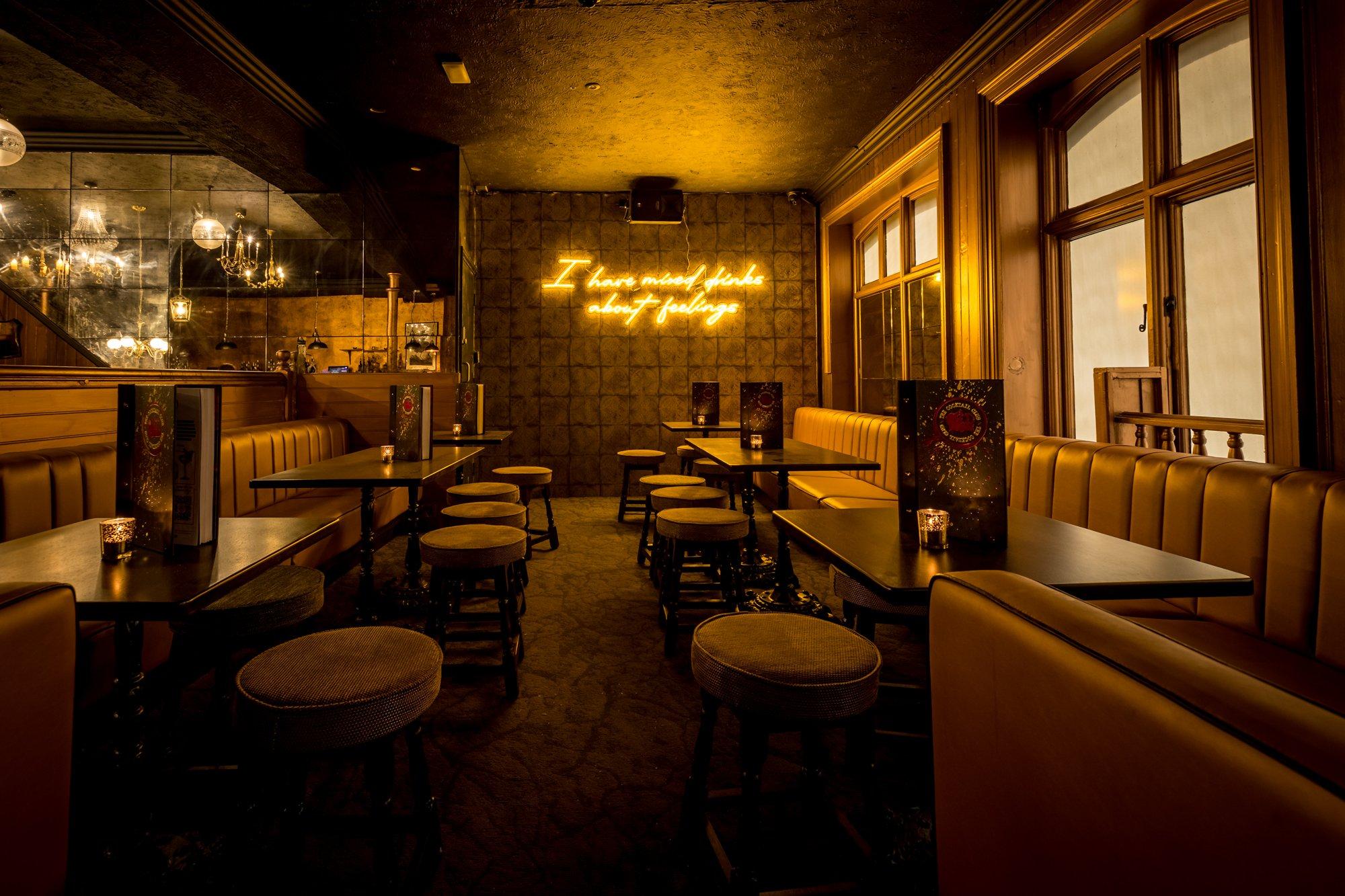Booth and stool seating area featuring a yellow neon sign