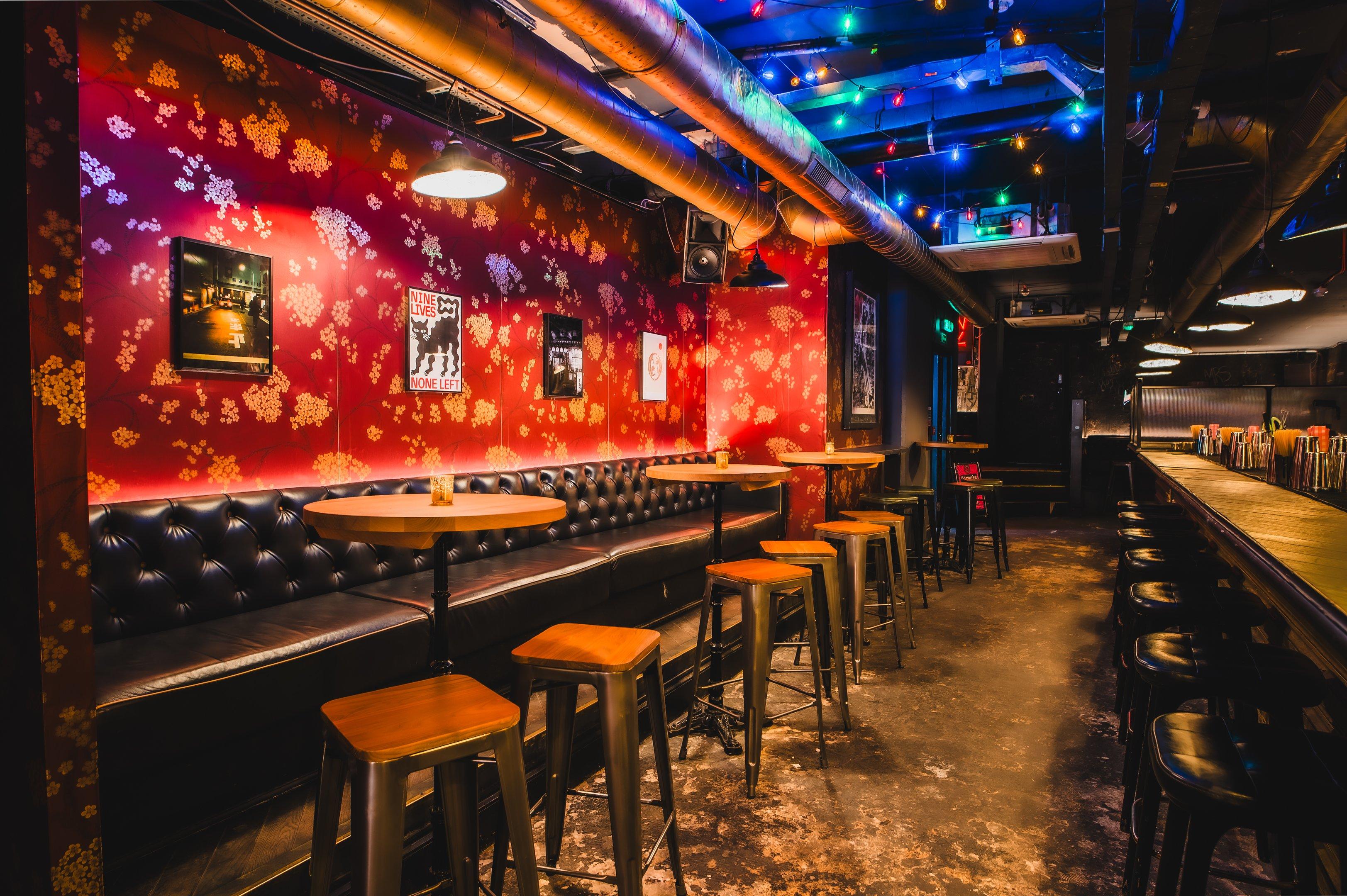Retro floral wallpaper and long black leather booth seating bar area