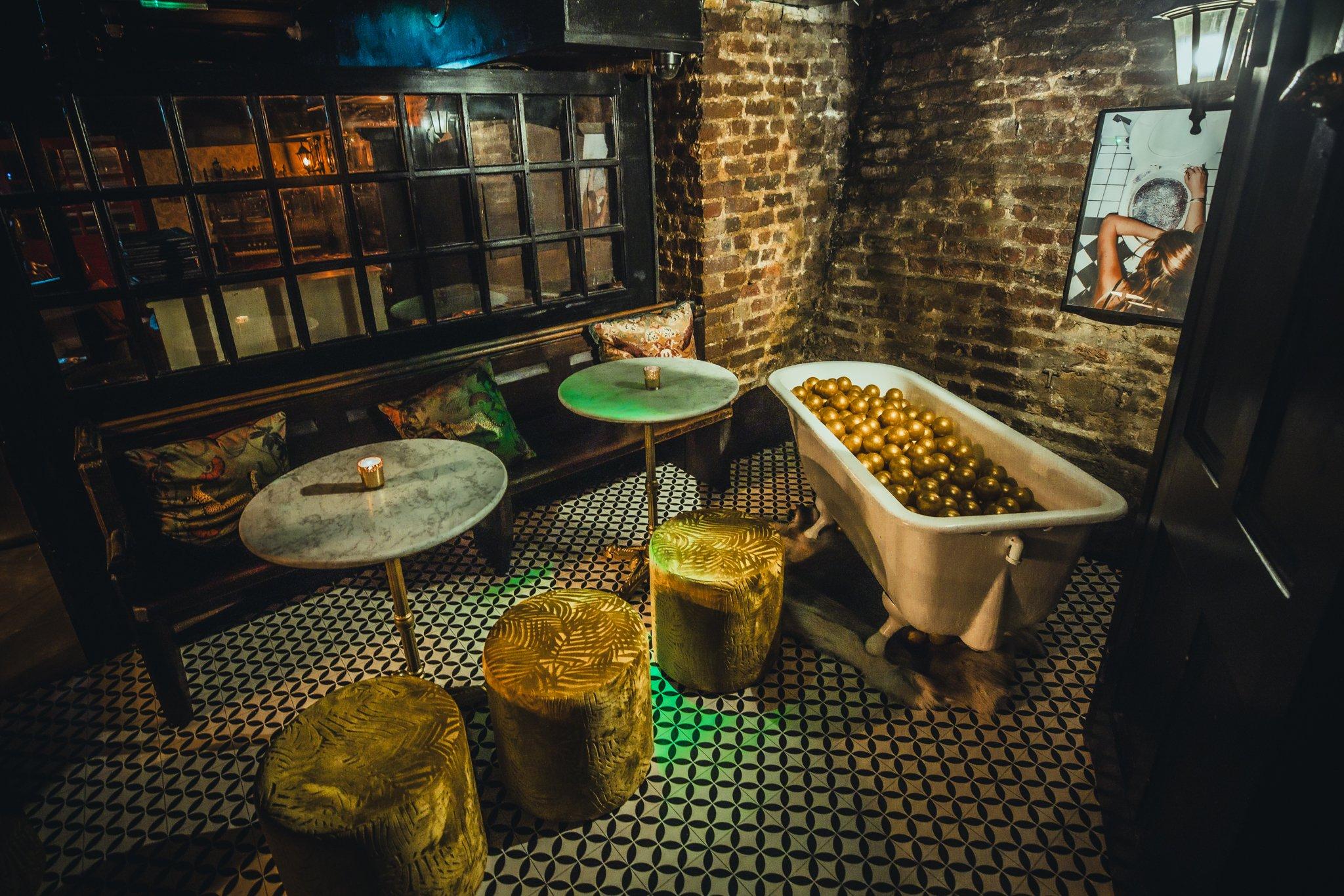 A bar area with decor taking inspiration from a retro bathroom with a bath full of ball pit balls