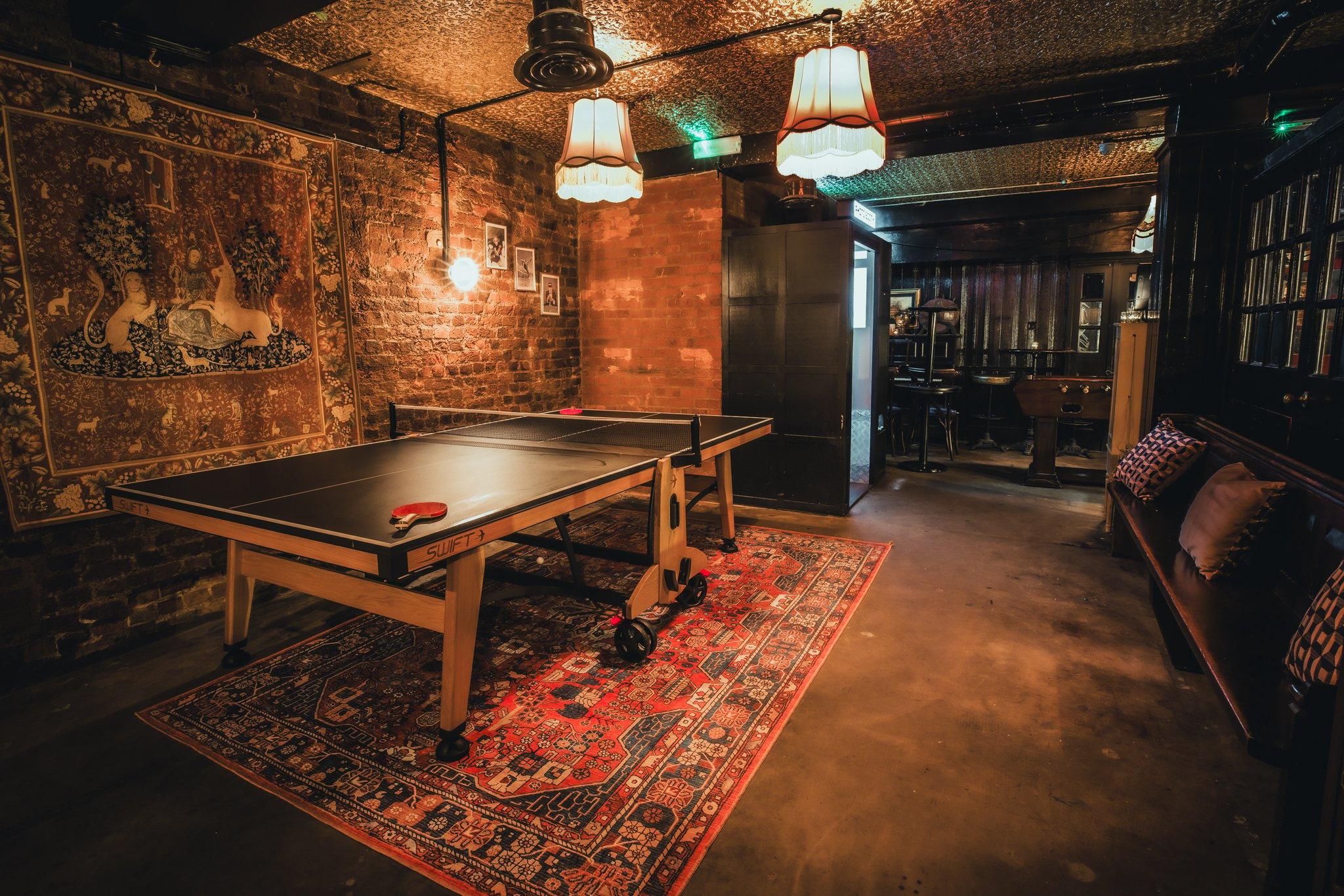 A private area of a bar with exposed brick walls and a ping pong table
