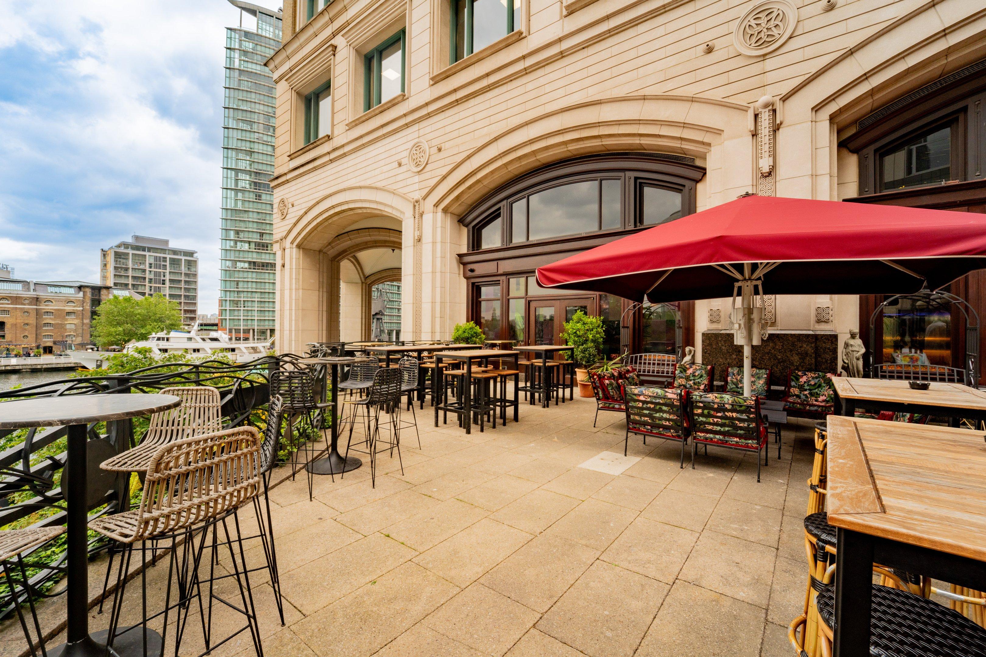 A outside terrace area overlooking a river with tables and seating