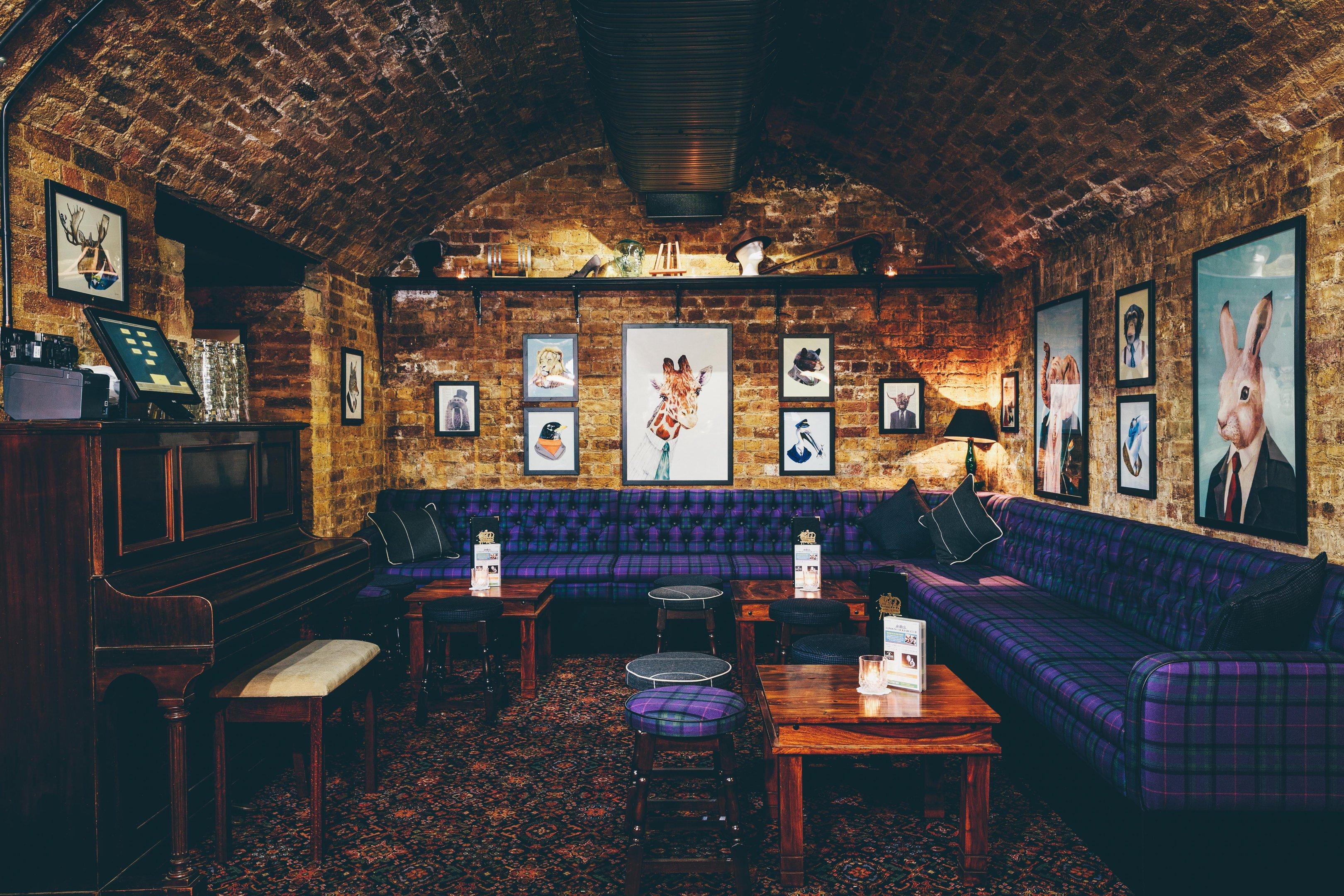 A seated area in a bar with exposed brick walls and piano