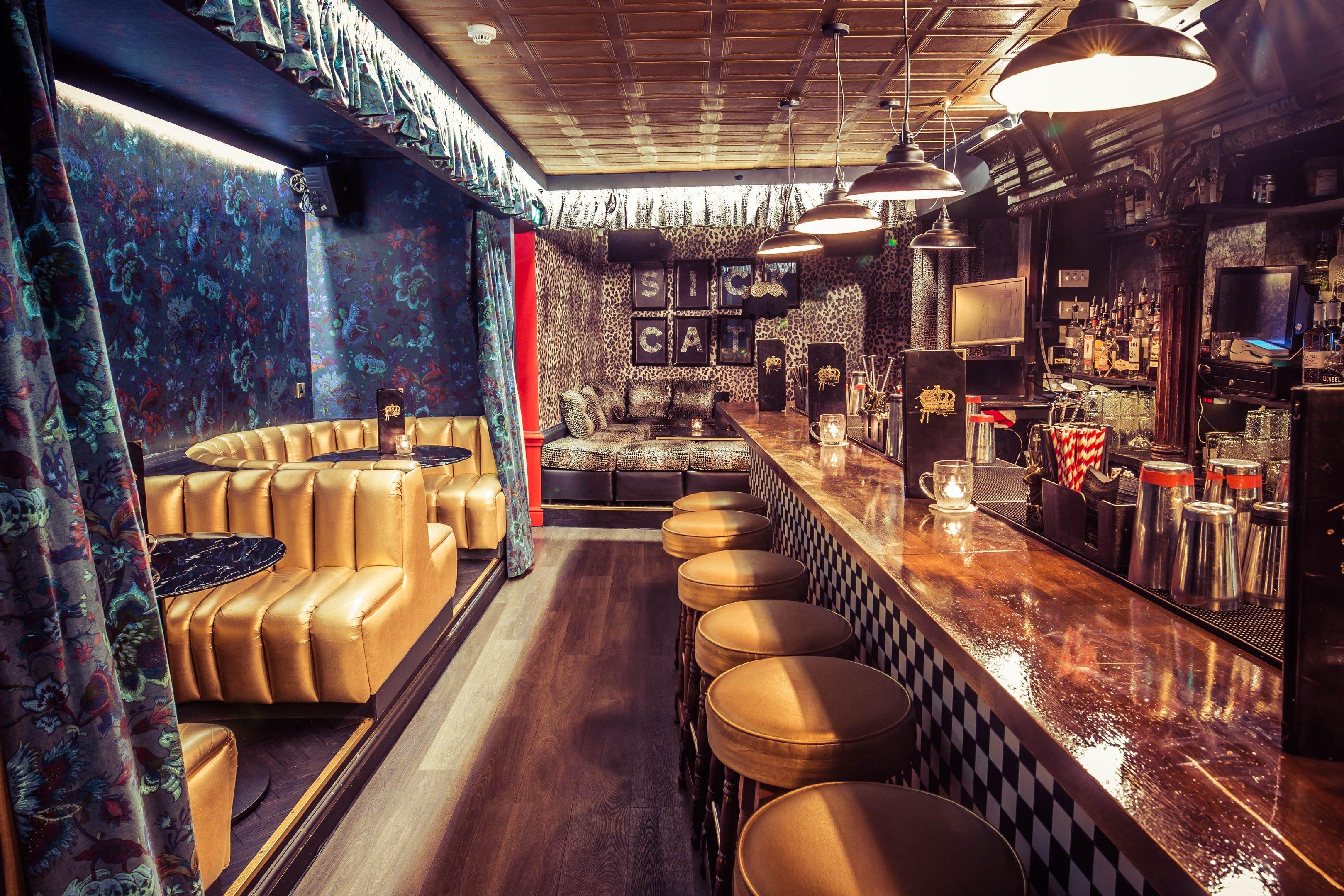 A bar area with bold wallpaper and checkerboard bar font and gold seating