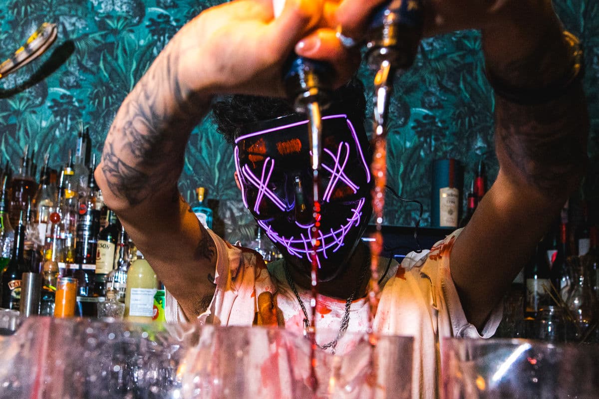 A bartender in a Halloween costume pouring drinks