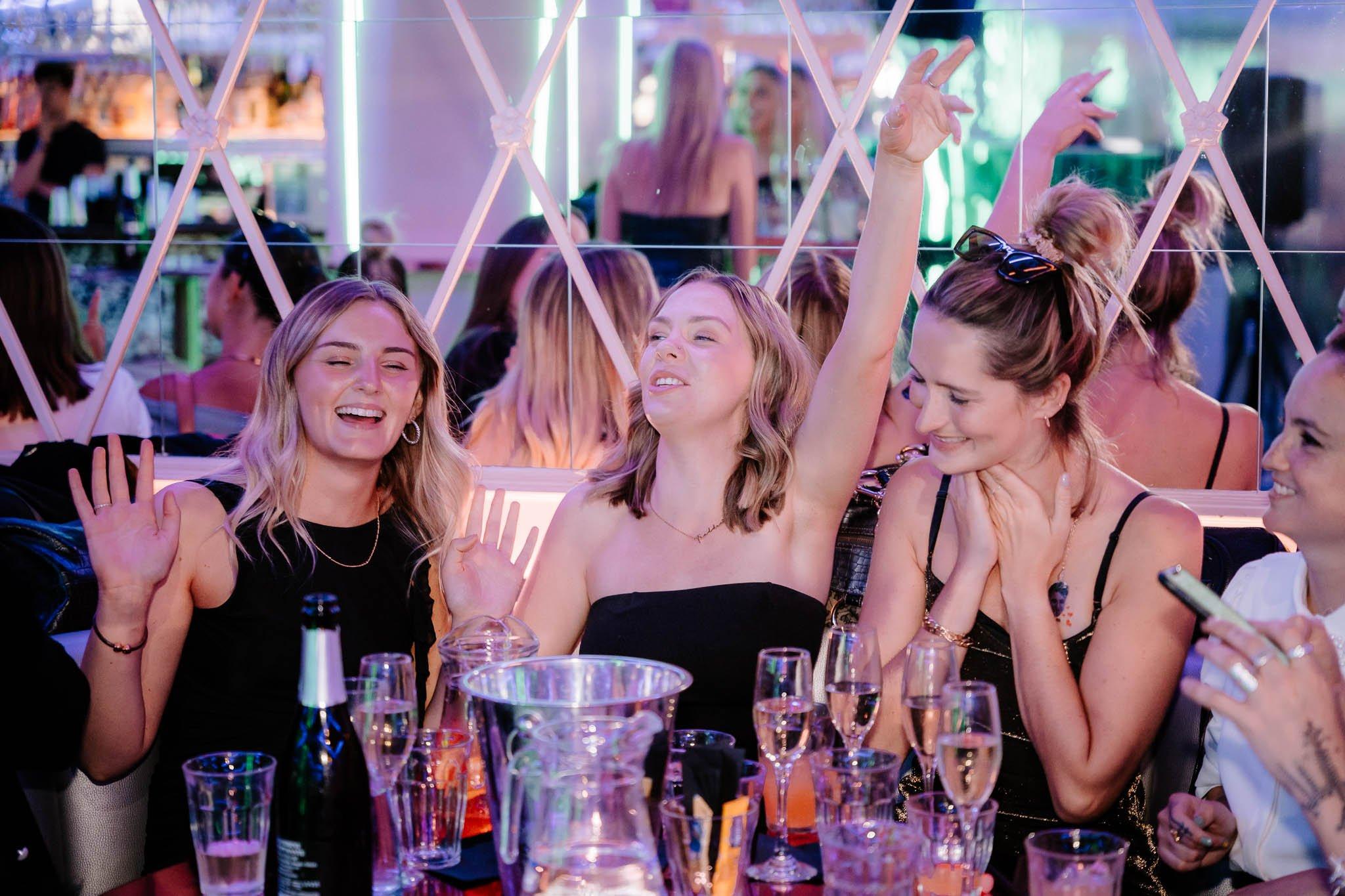 Women drinking and singing at a table in Tonight Josephine