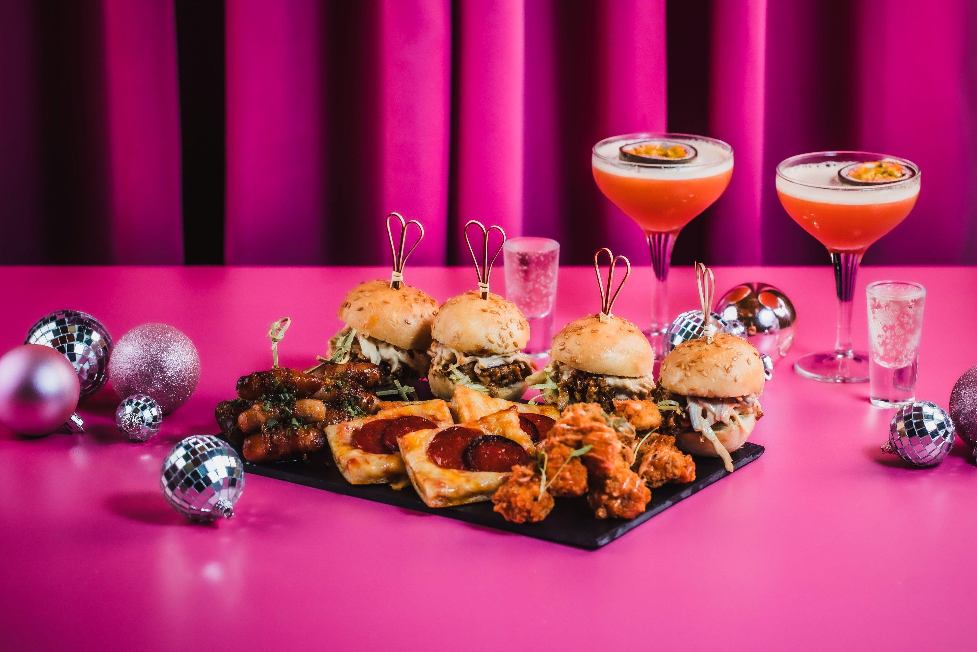 Christmas food platters with cocktails on a pink tabletop in Tonight Josephine