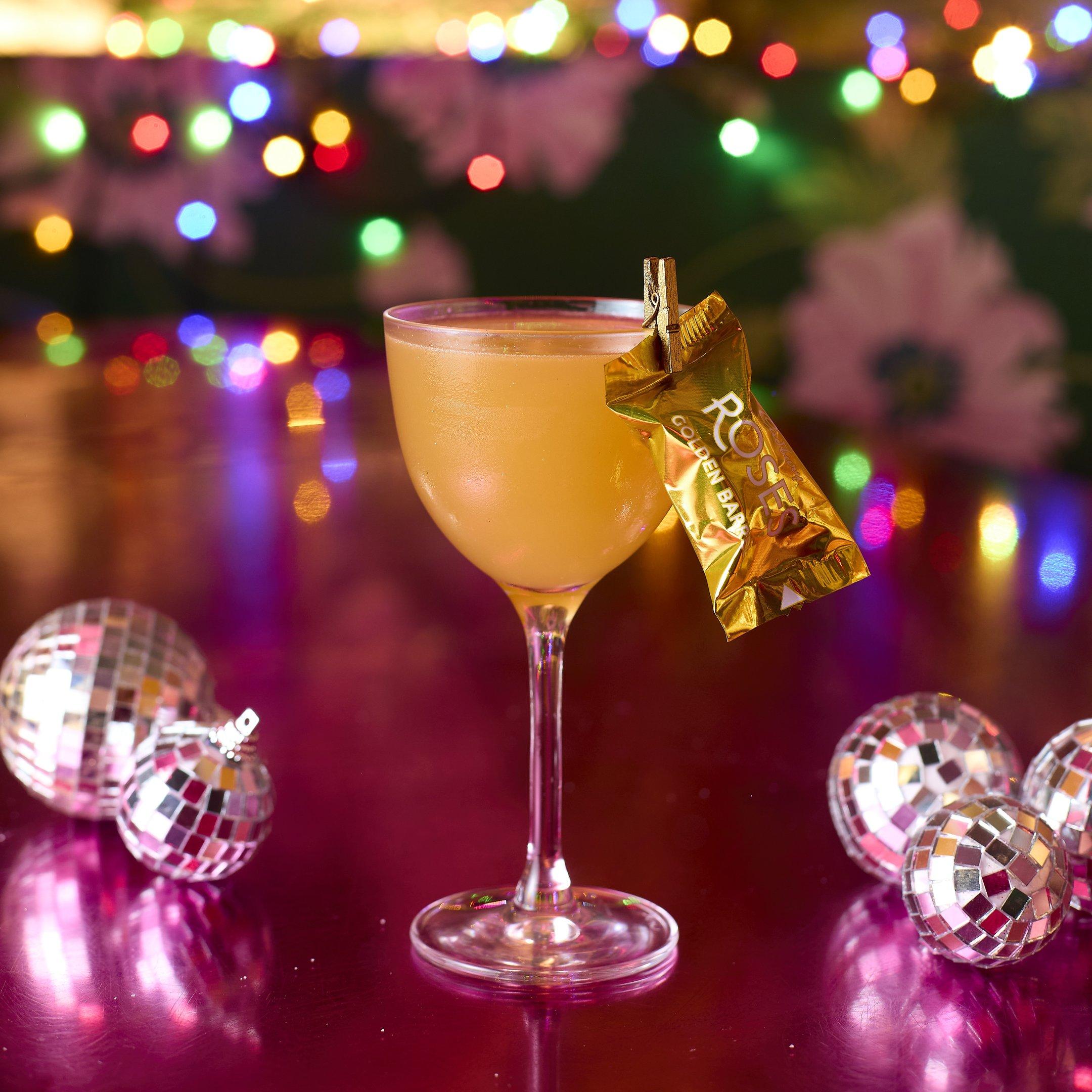 A golden festive cocktail with a Gold Roses chocolate garnish