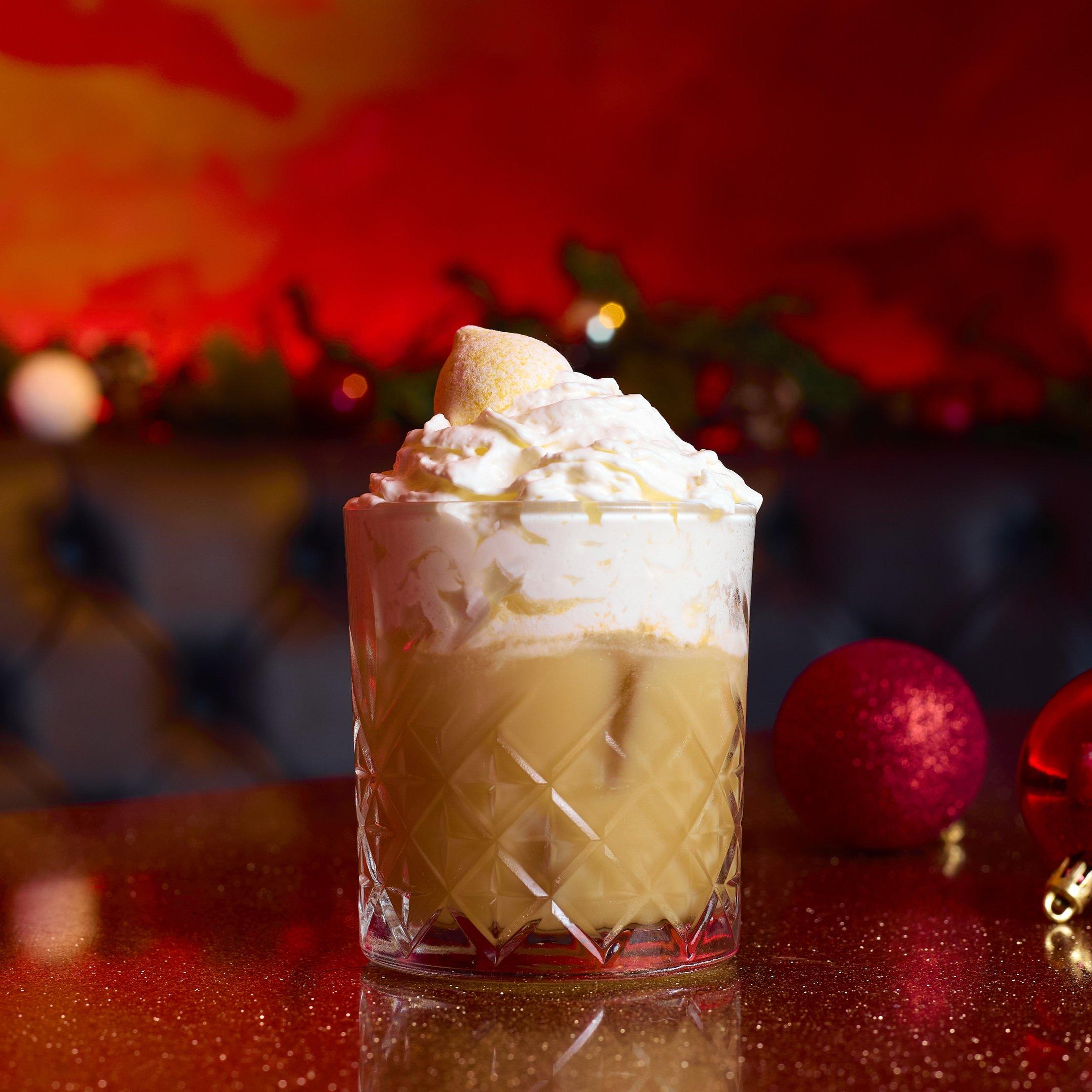 An eggnog cocktail in a short glass topped with cream