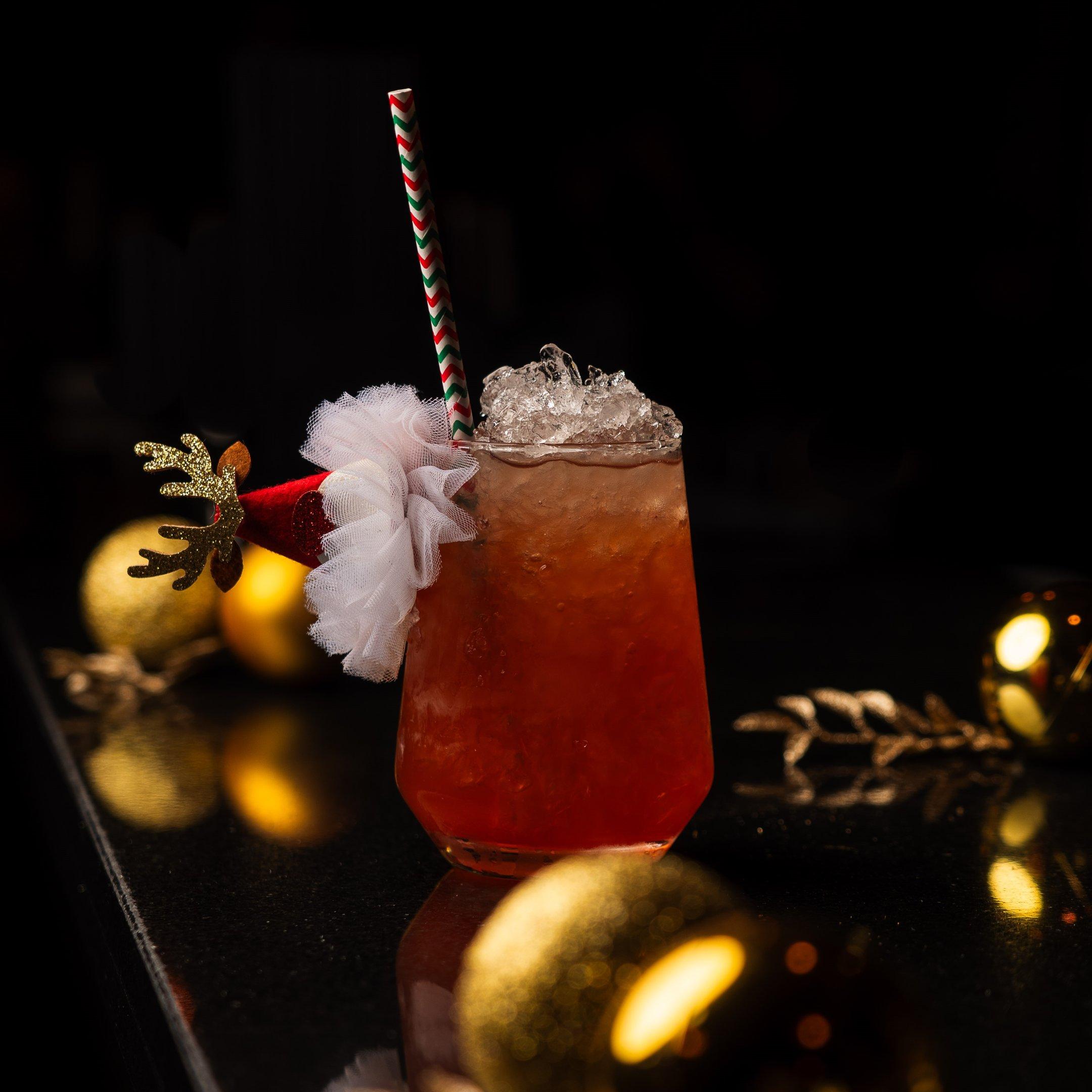 A Christmas cocktail with a Santa hat garnish