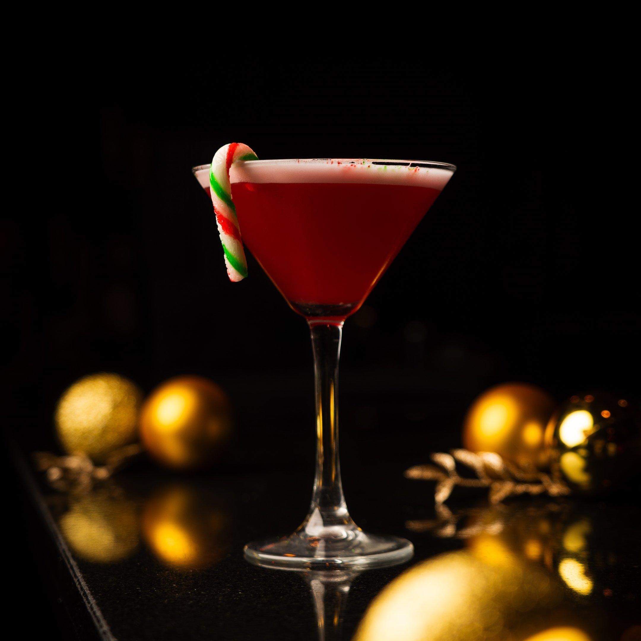 A Christmas cocktail with a mini candy cane garnish