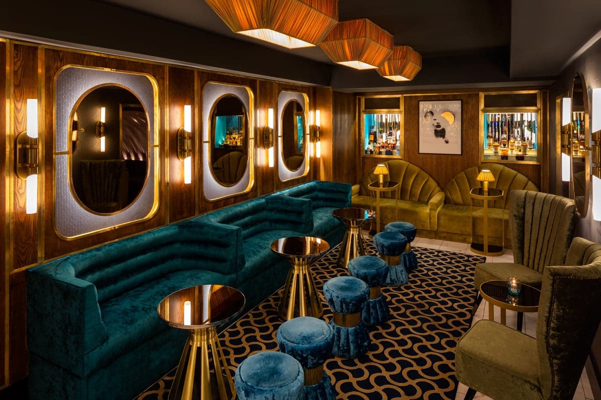 An interior shot of Disrepute with patterned carpets and velvet seating