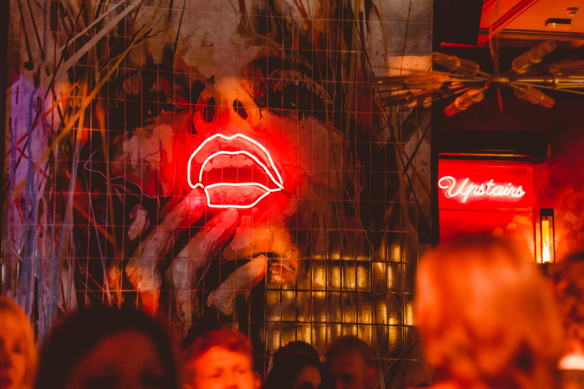 Wall art with a red neon light lips sign in a Dirty Martini bar