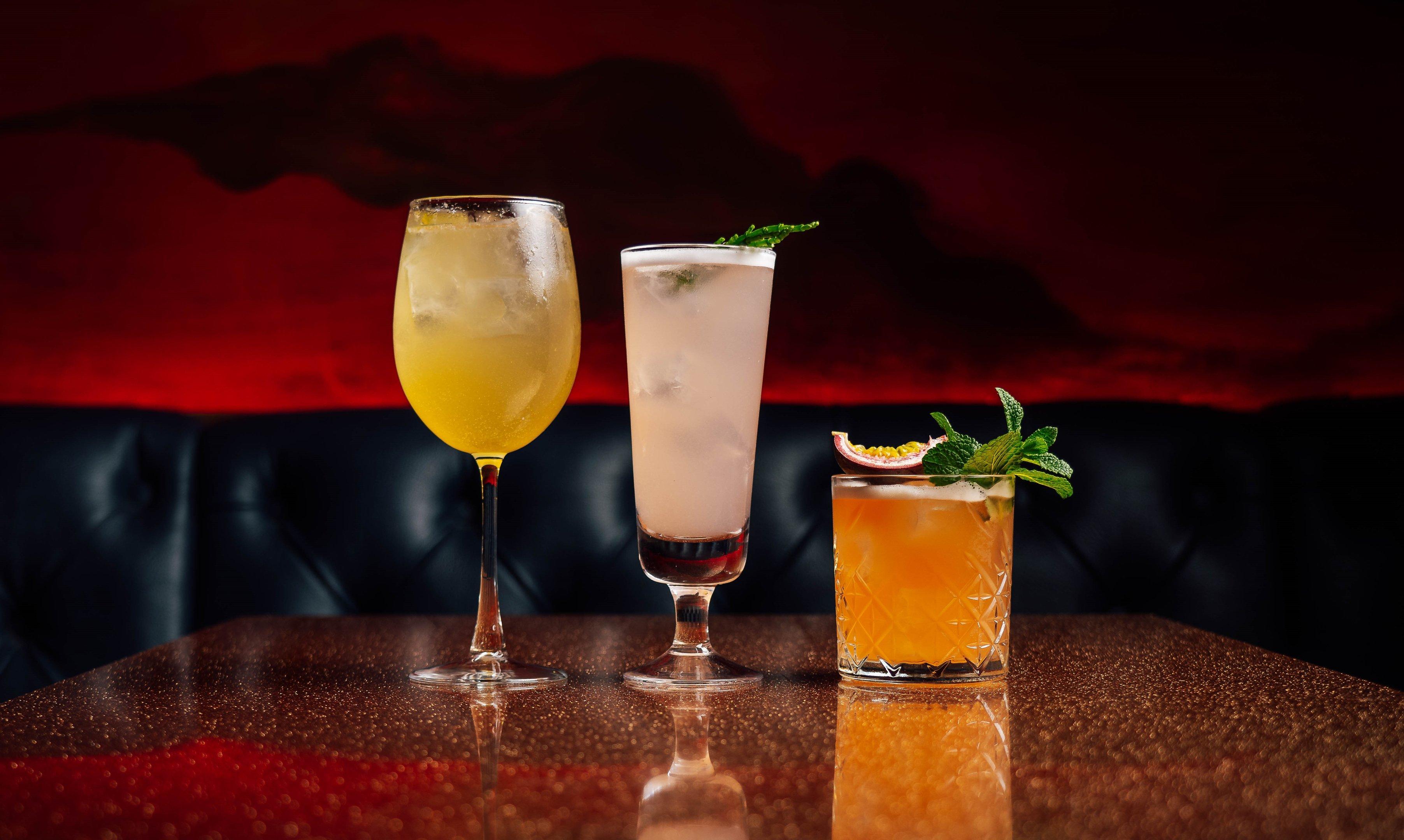 Three mocktails lined up on a table with fresh garnishes in The Escapologist