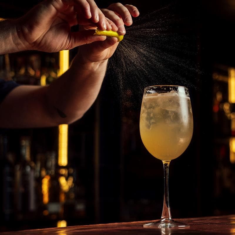 A bartender garnishing a mocktail with a lemon