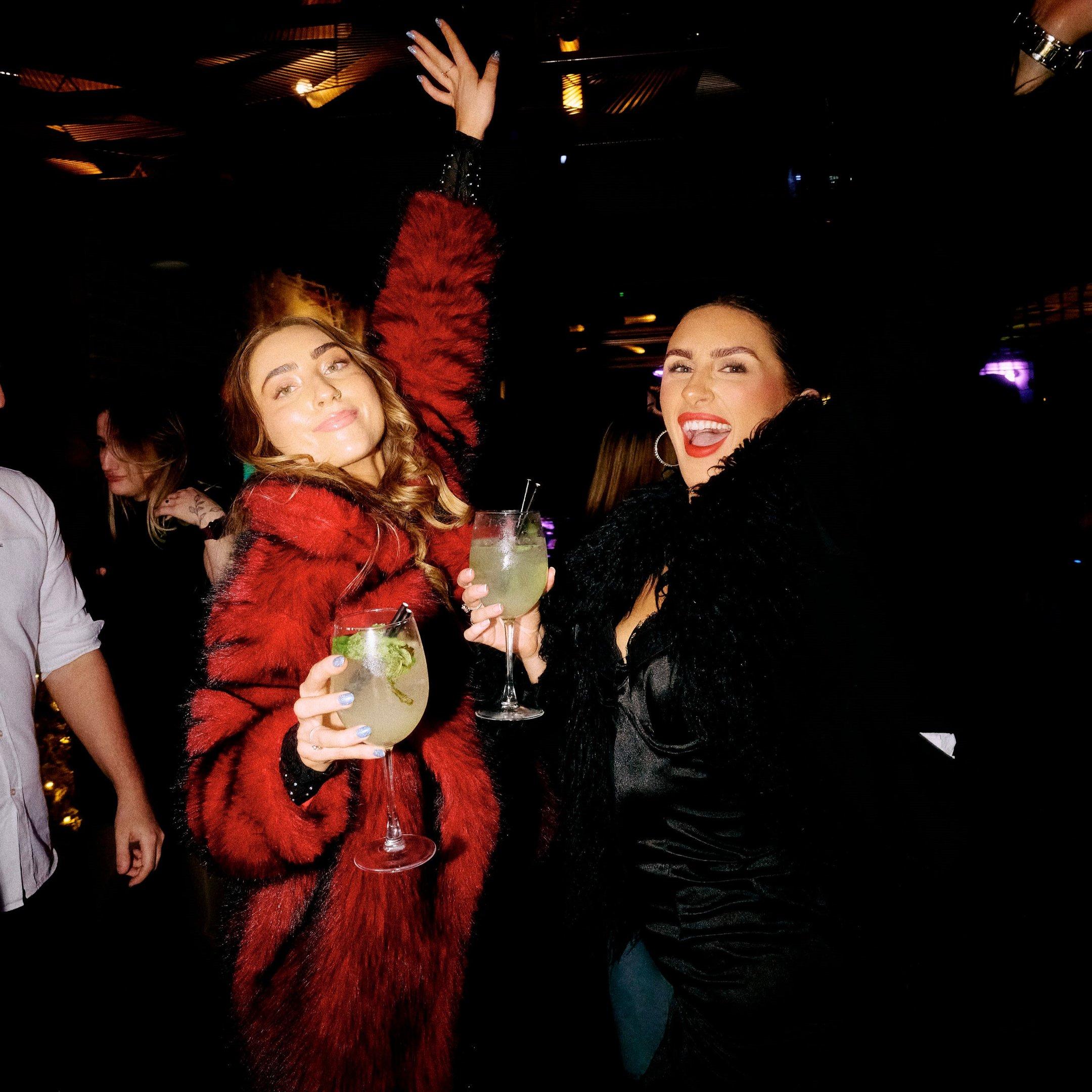 Two women in fur coats dancing in Dirty Martini