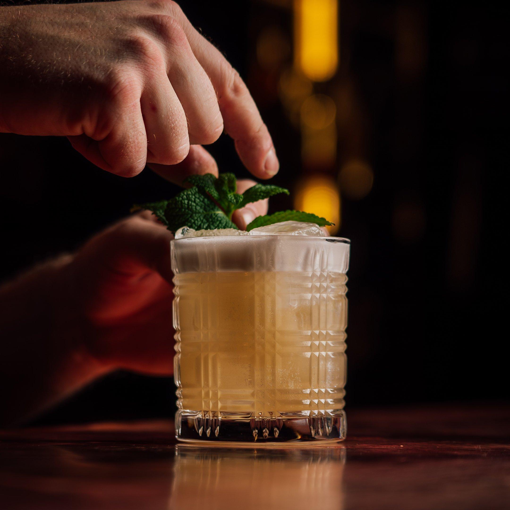 Hands putting a garnish onto the Banana Duchess cocktail in The Escapologist