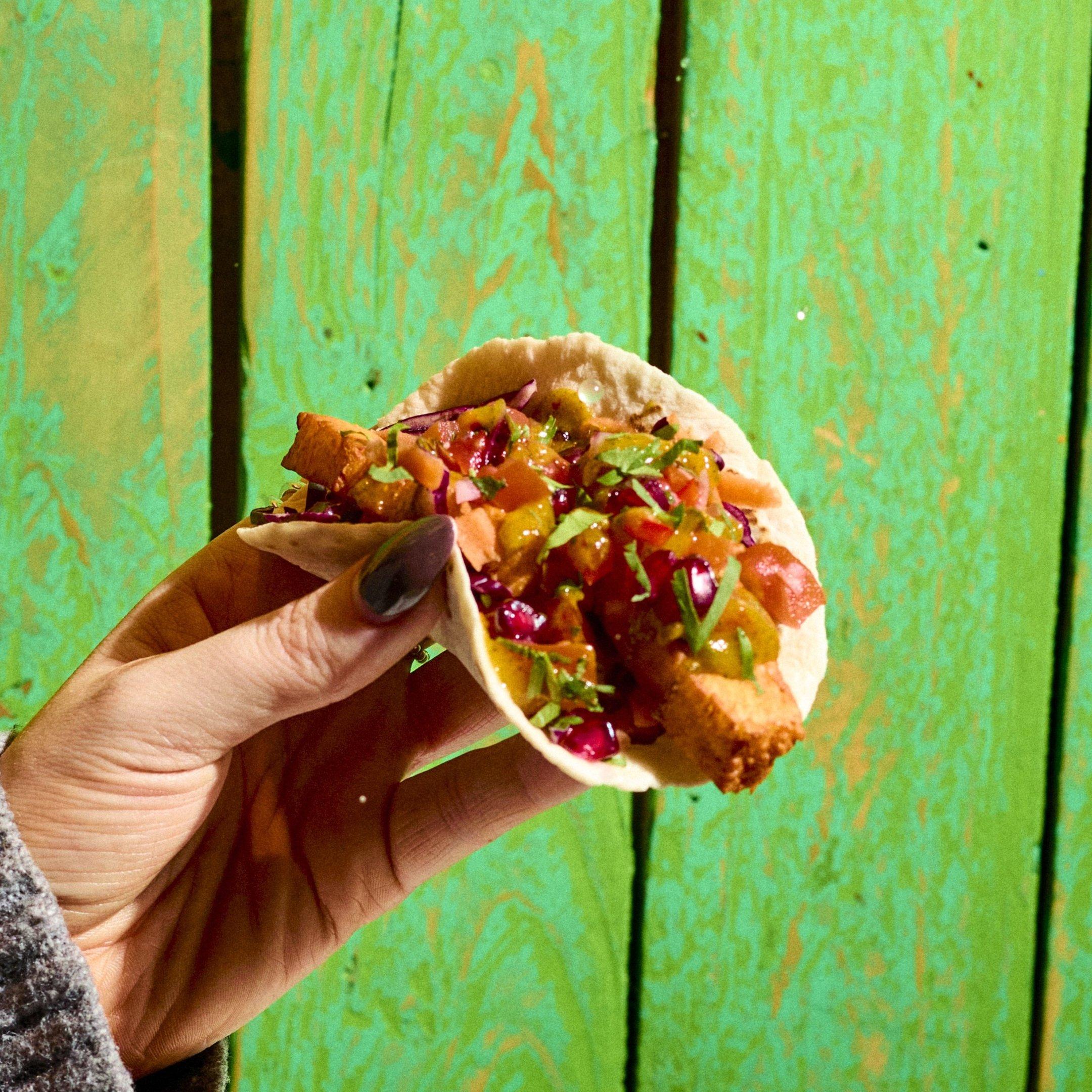 A hold handing a Halloumi Taco in Barrio