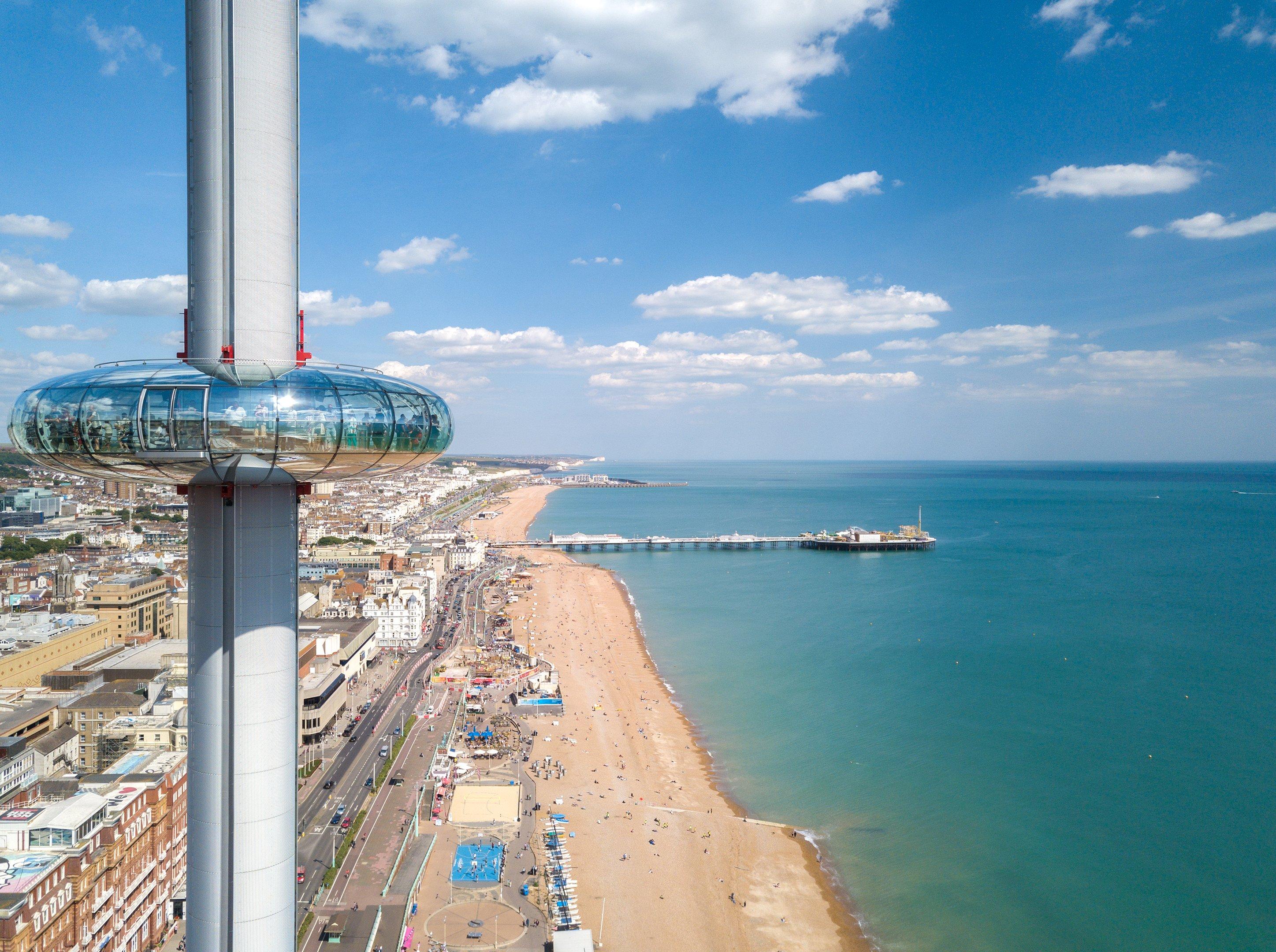 An image of the Brighton i360 tower with the Brighton beach and pier in the distance