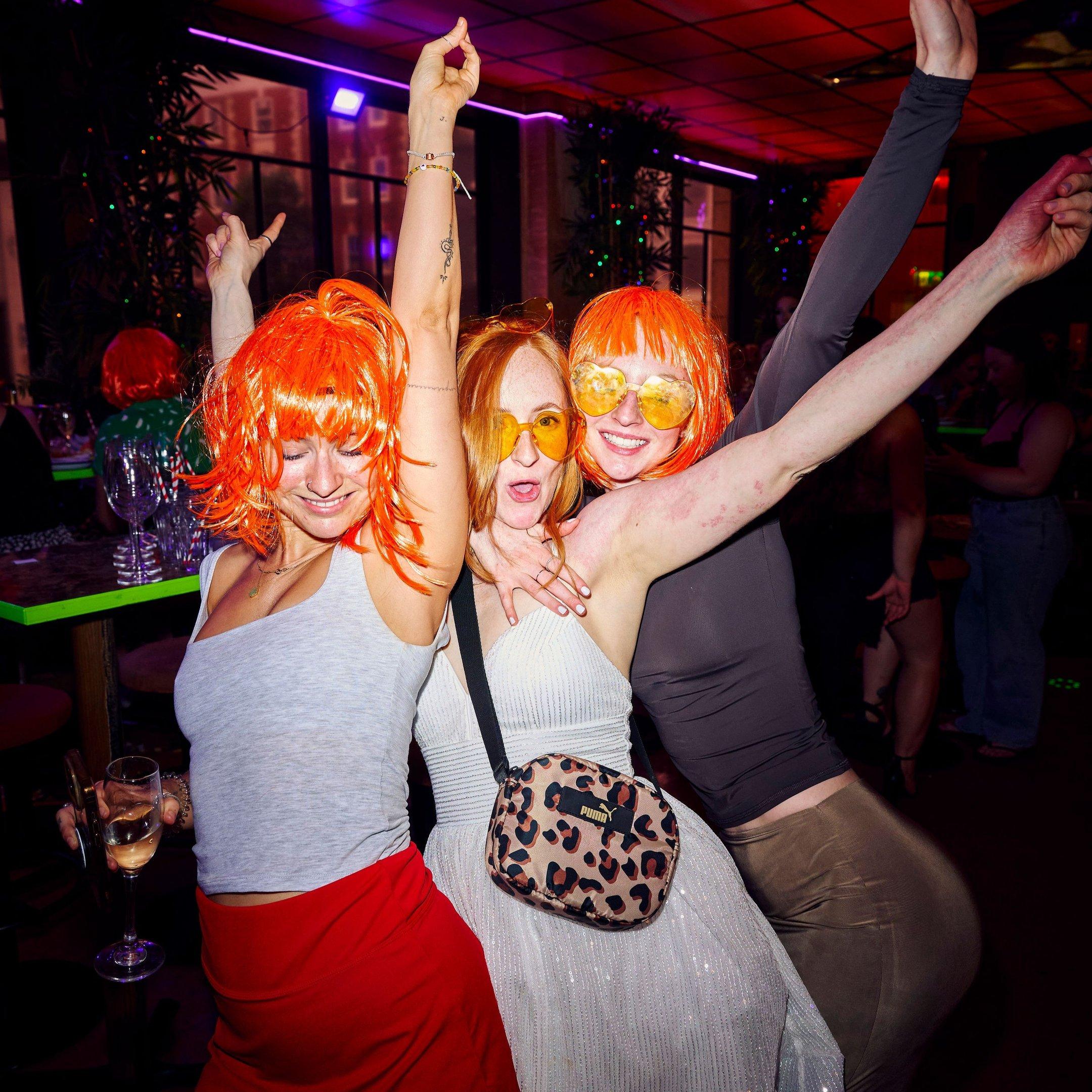 Guests wearing wigs and dancing in Nikki's bar