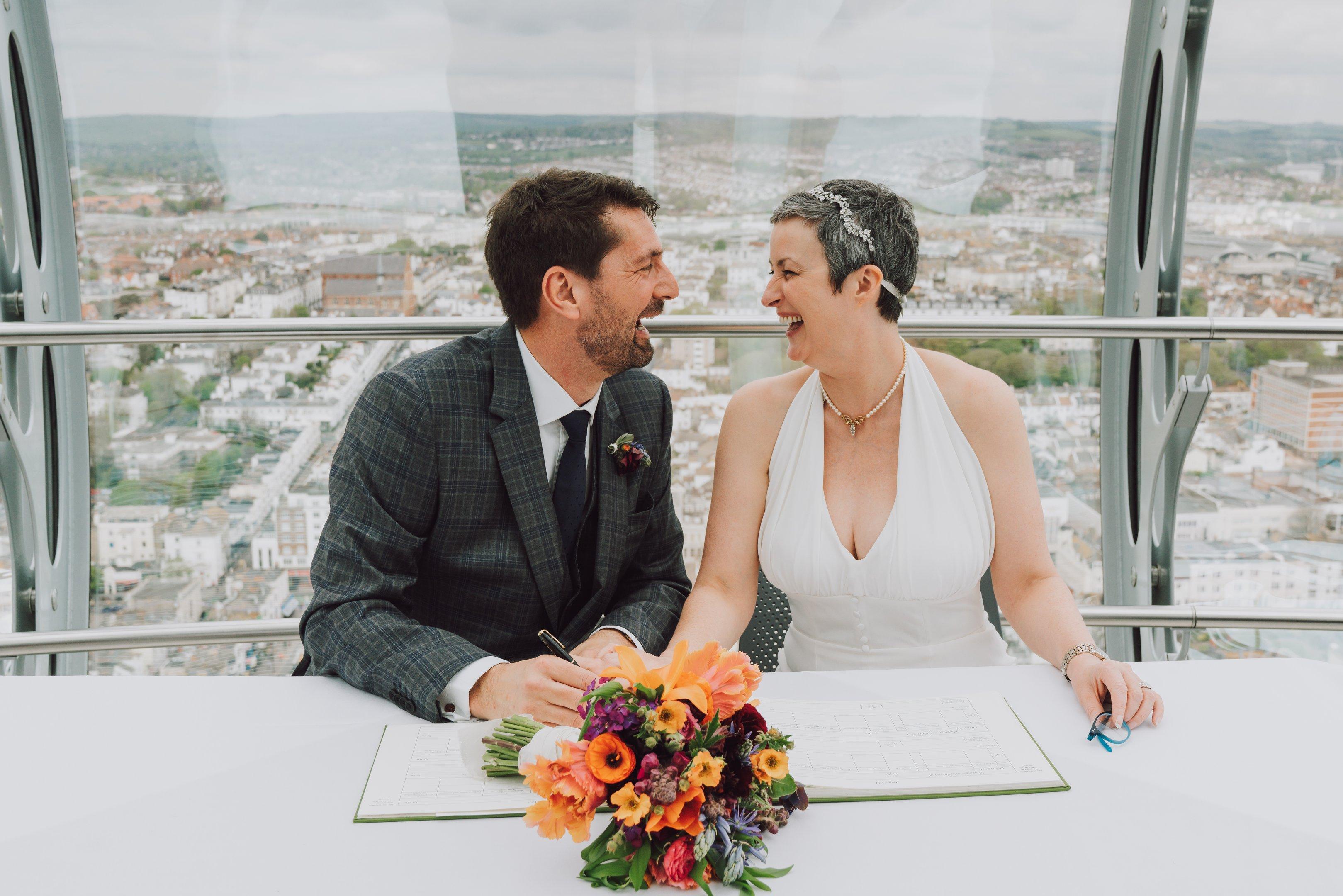 A newly married couple sitting and signing a book in the Brighton i360 pod
