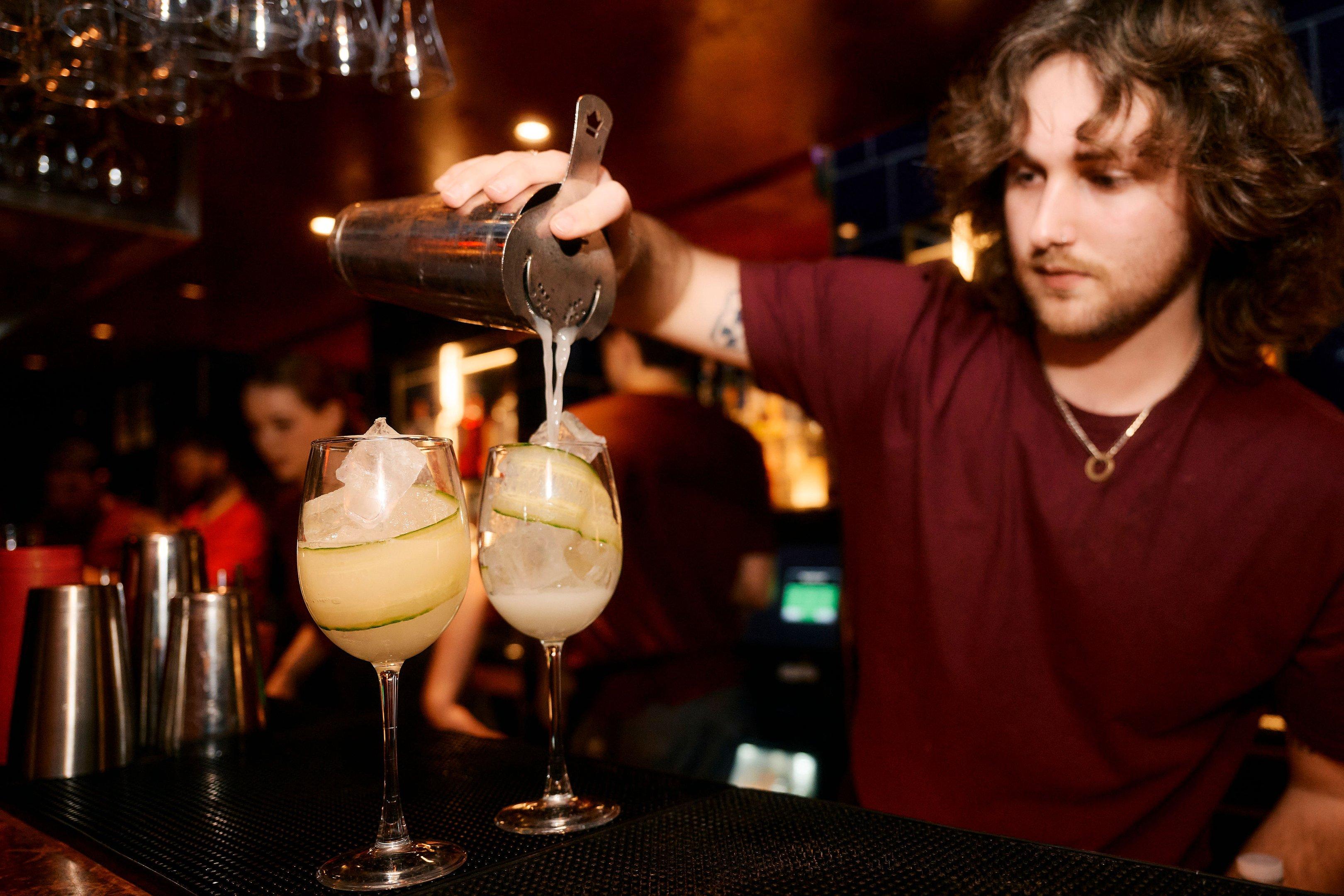 A bartender pouring two cocktails on the bar in The Escapologist