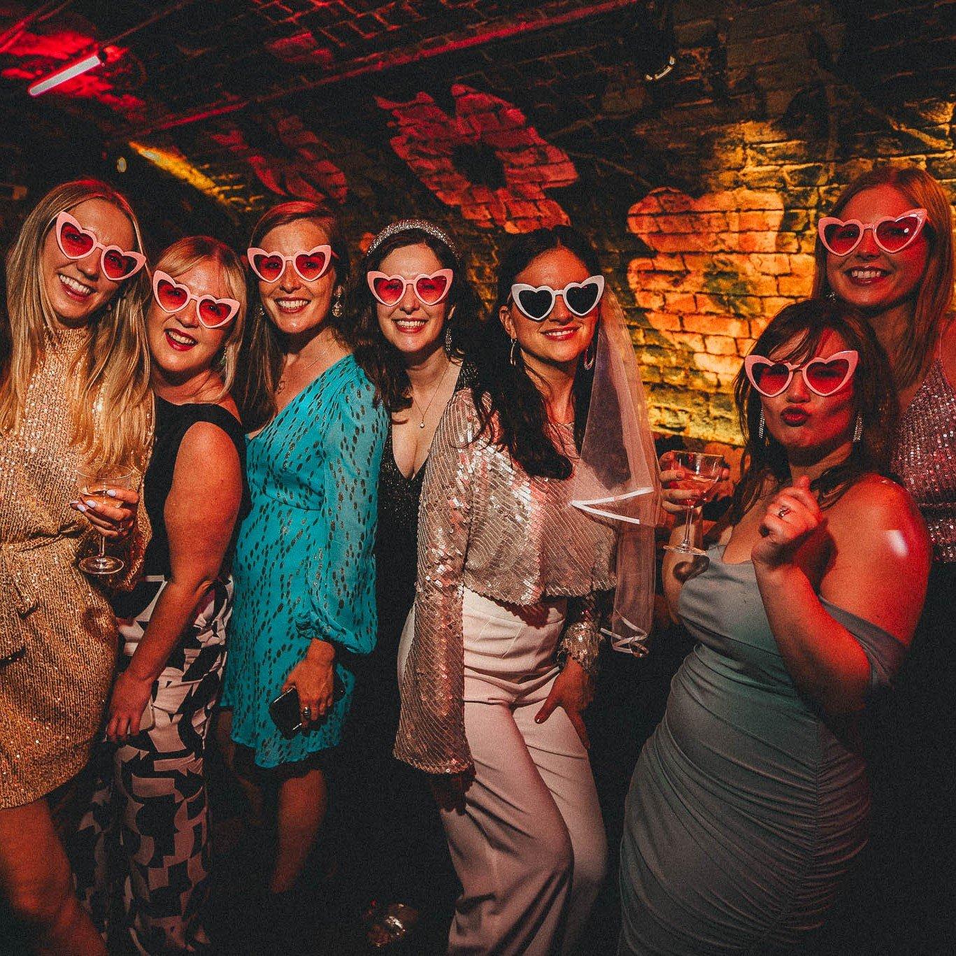 A group of women posing for a photo in Blame Gloria wearing heart sunglasses
