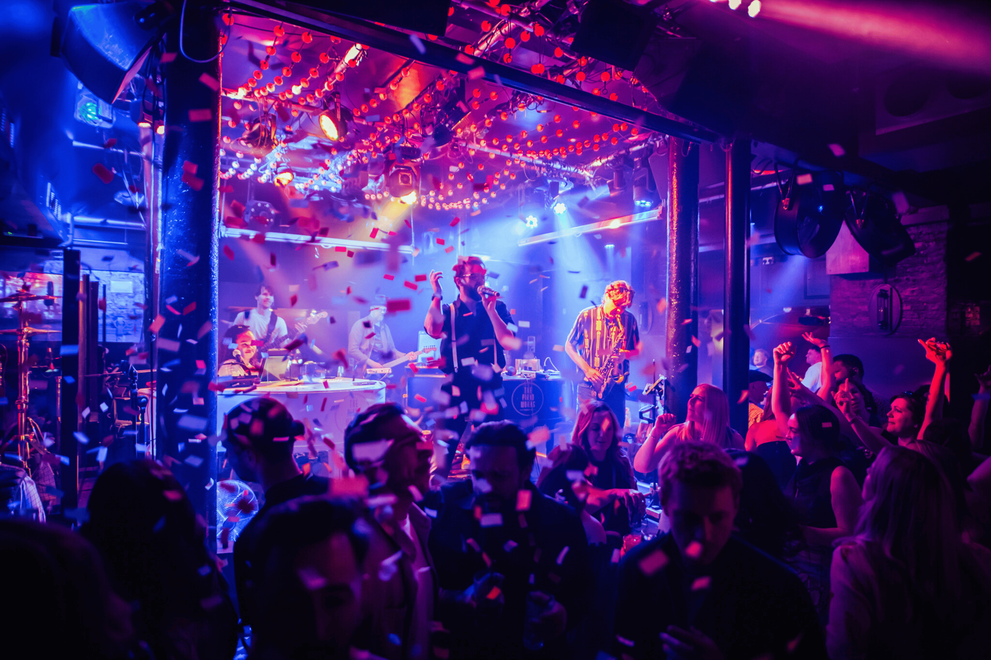 A live band performing at The Piano Works with confetti falling and guests dancing