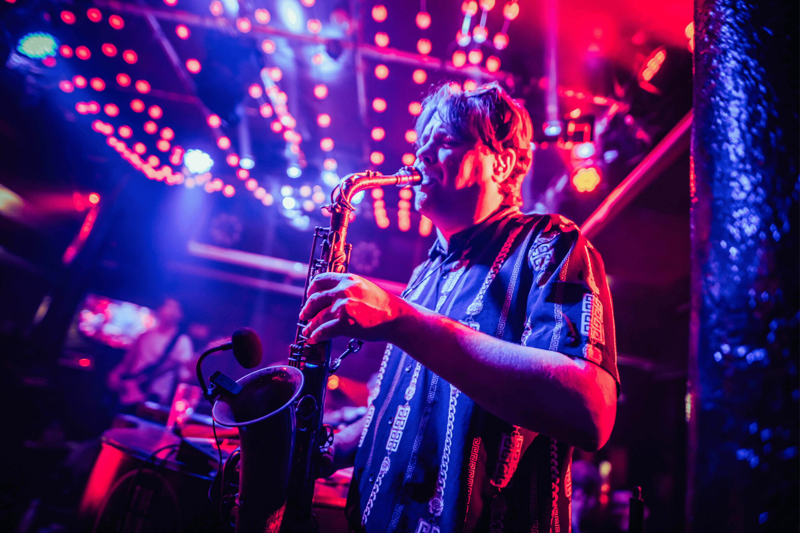 A band member playing the saxophone on the stage in the Piano Works