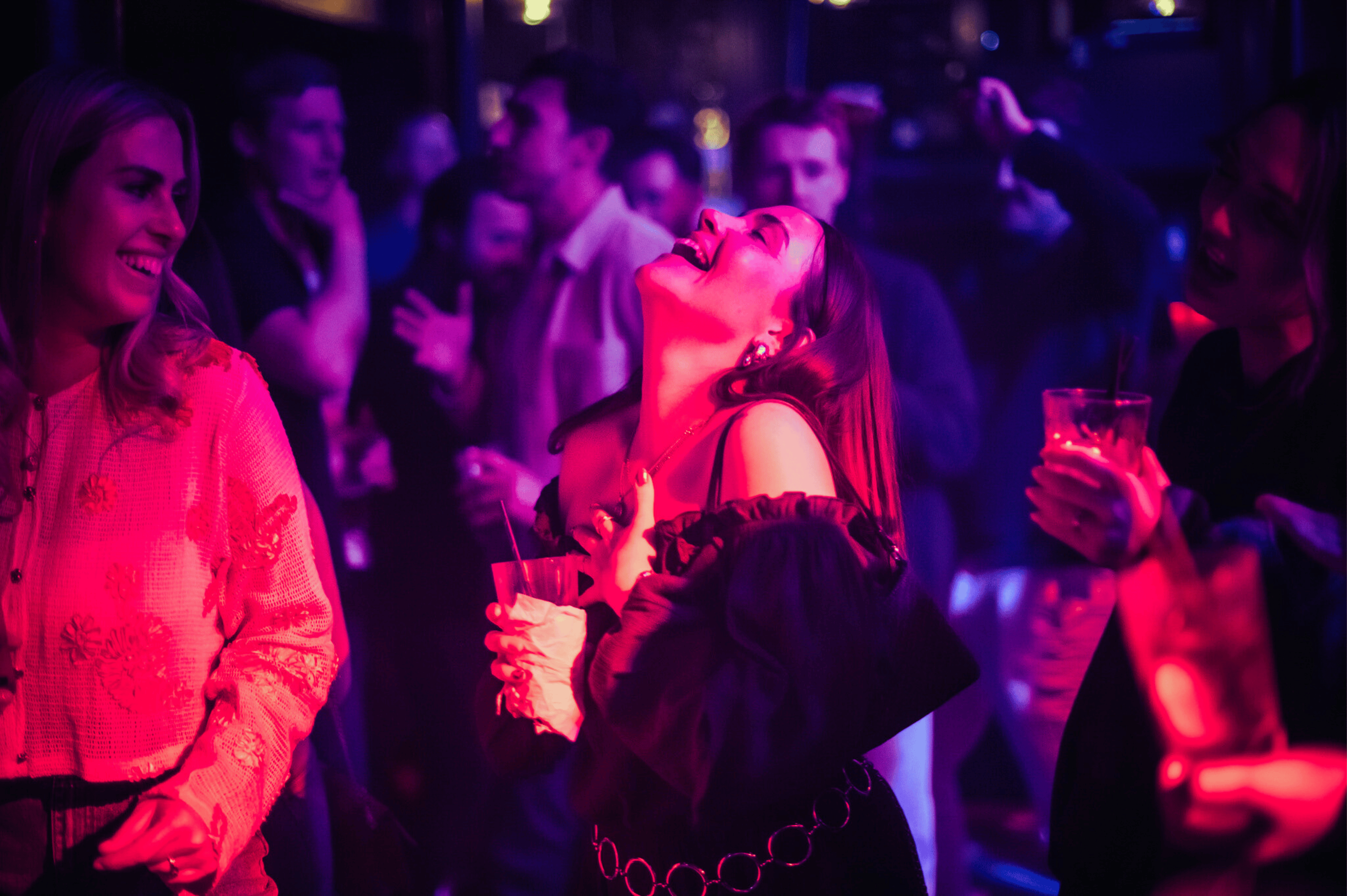A woman singing along to a live band with a drink in hand in The Piano Works