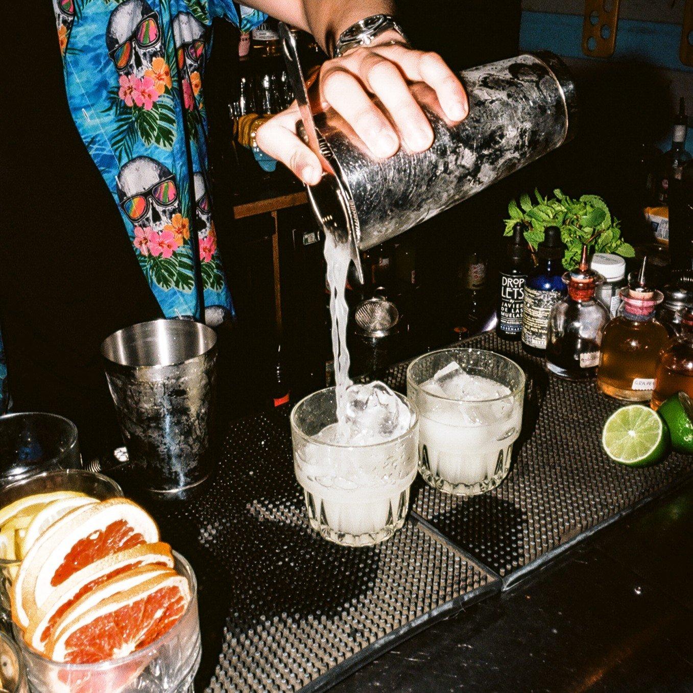 A bartender pouring two Tommy's margaritas on the bar in Barrio