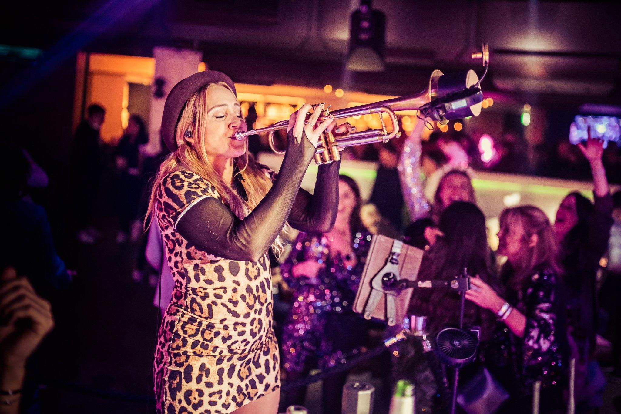 A female performer playing the saxophone on a stage in The Piano Works