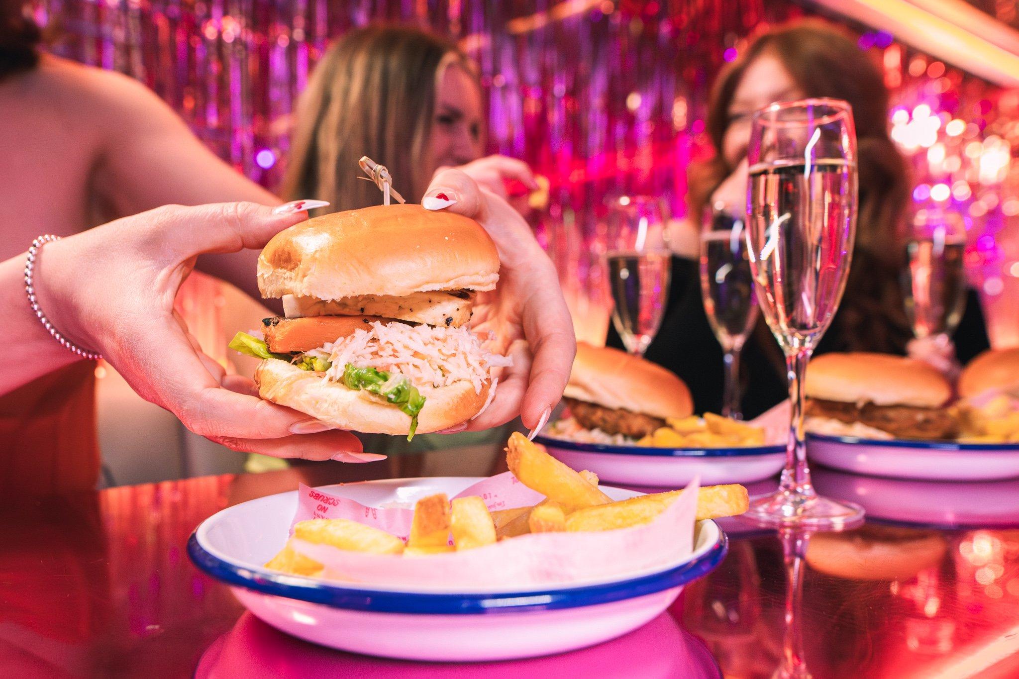 A bottomless brunch guest holding a burger in Tonight Josephine
