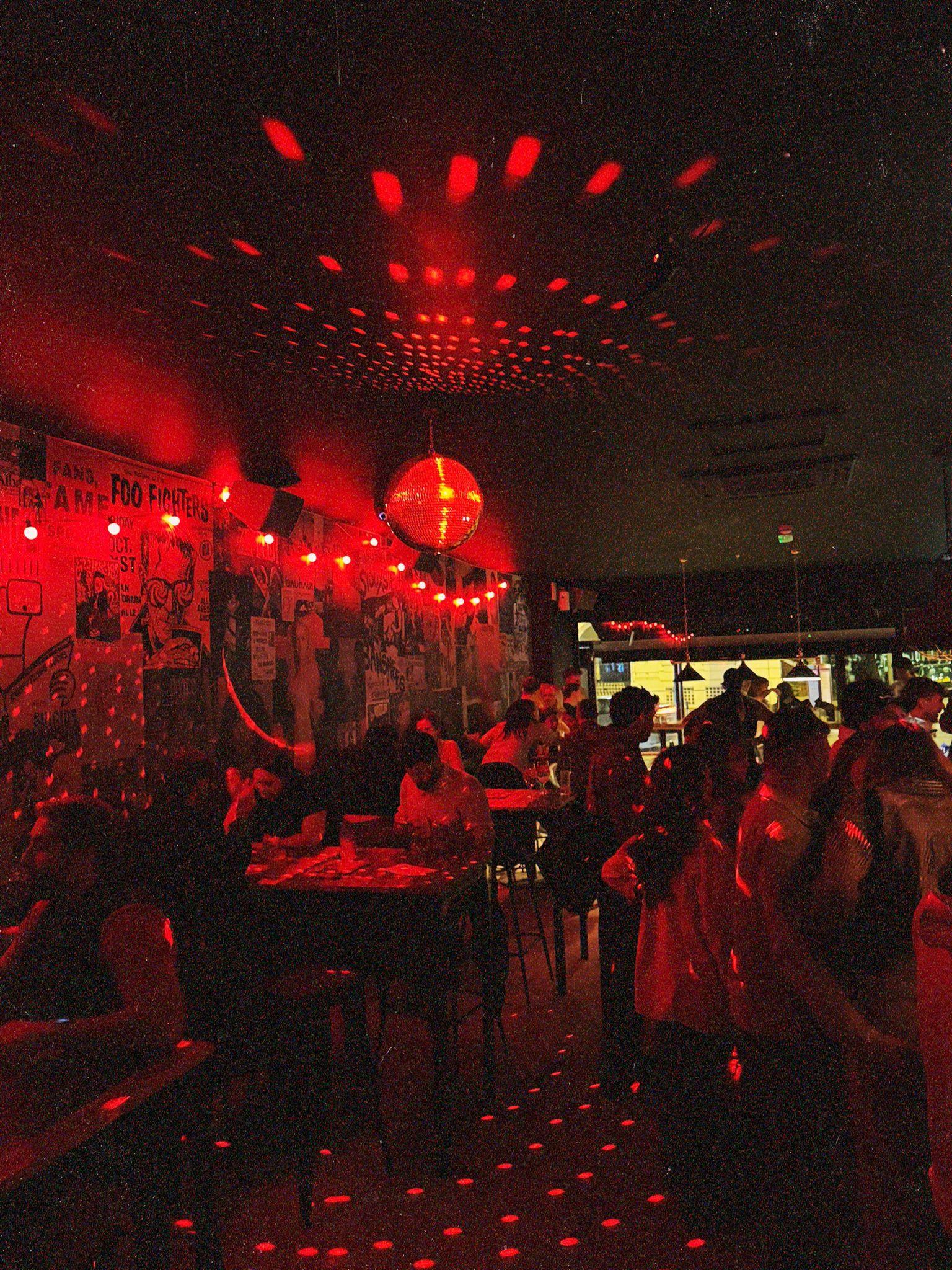 The inside of Afters bar with red lights and a disco ball shining on customers