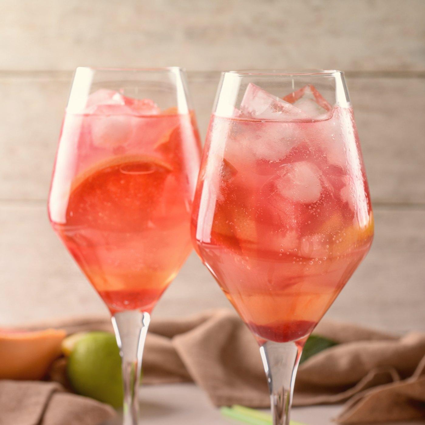 Two tall glasses of Passoã Spritz with ice and an orange garnish