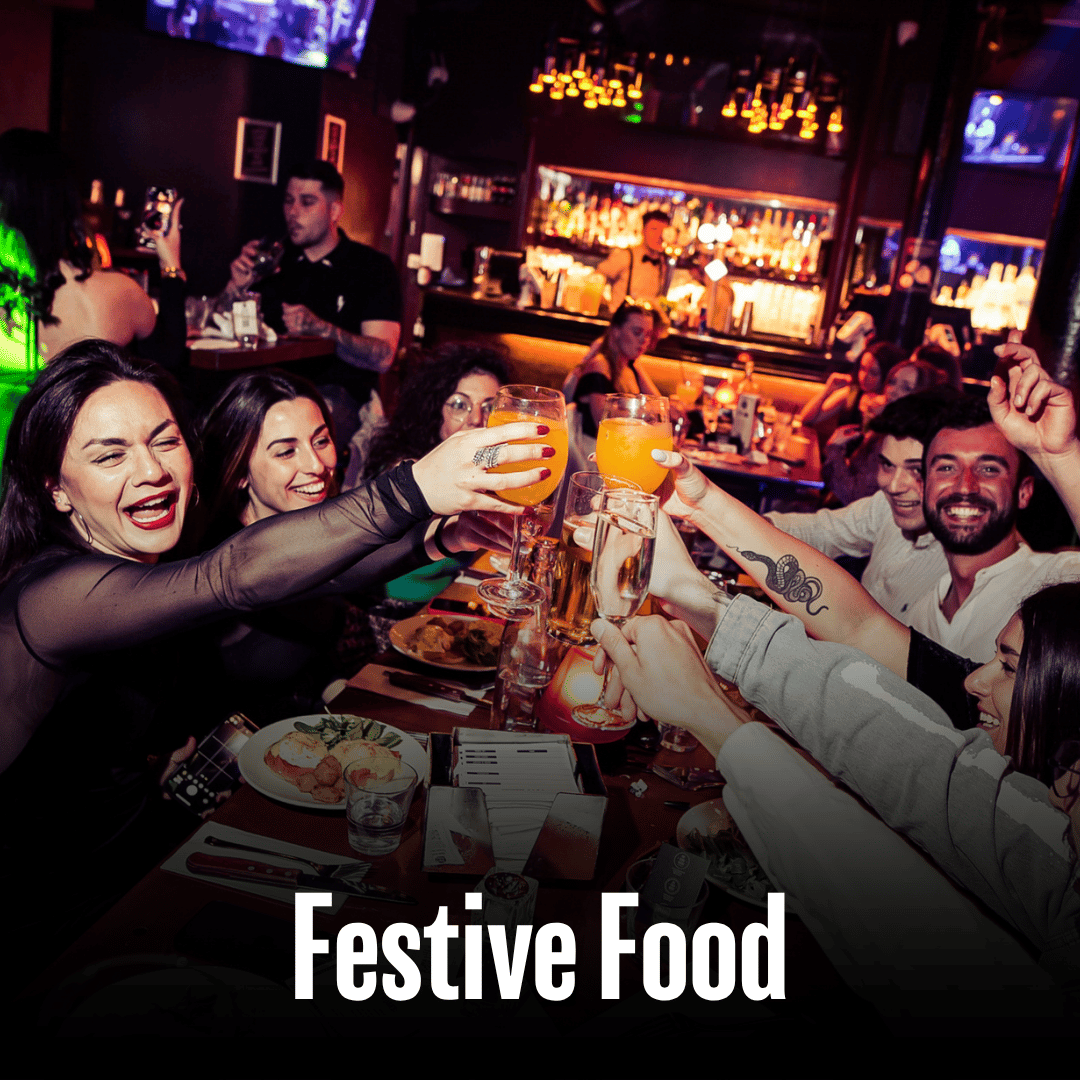 A group raising drinks over dinner at The Piano Works with the text Festive Food