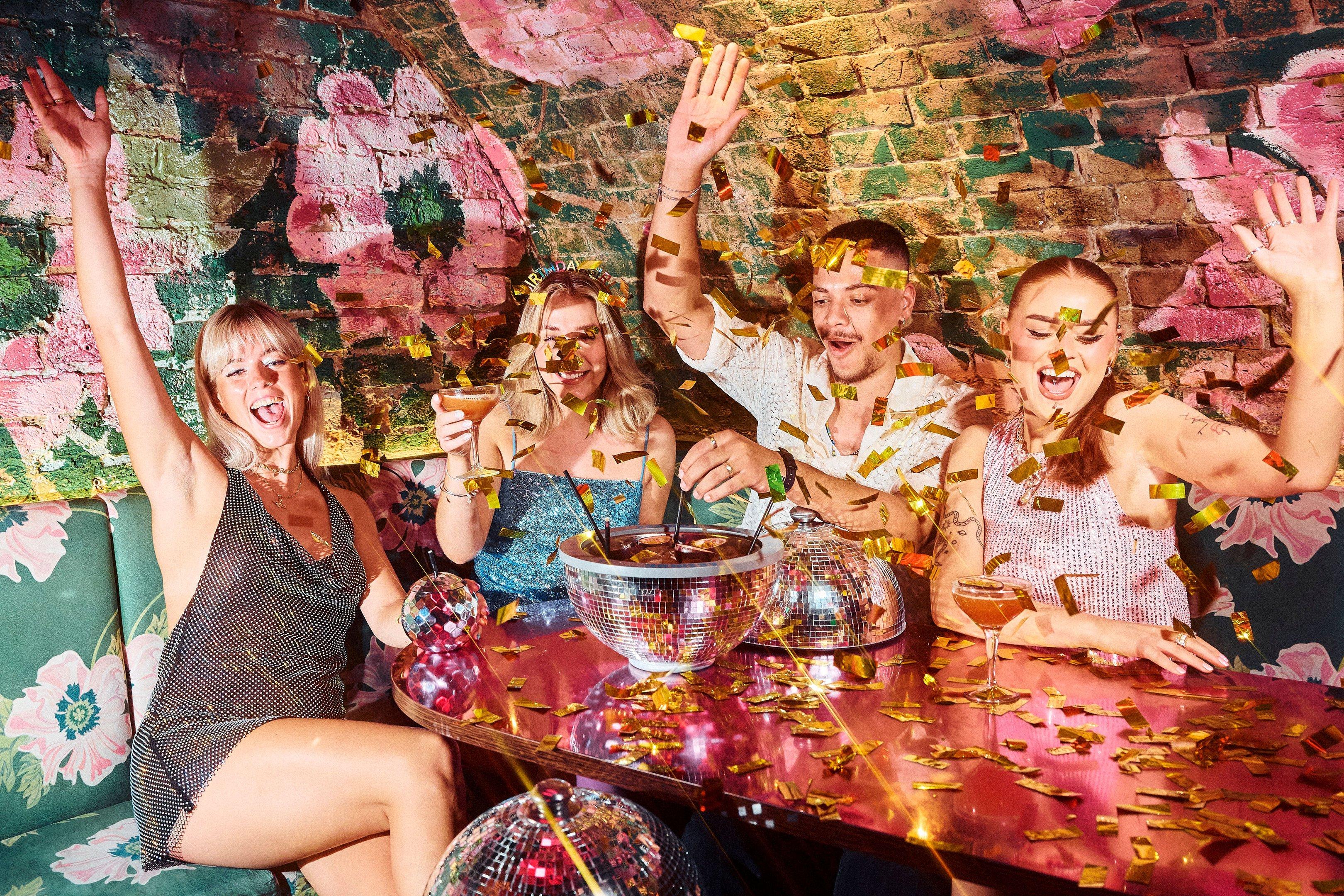 Friends celebrating with confetti and a disco ball sharer at Blame Gloria