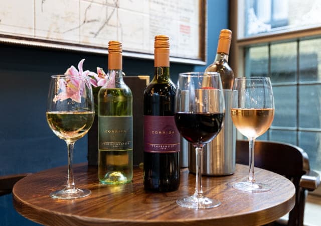 Glasses of red, white and rose wine in front of red and white wine bottles