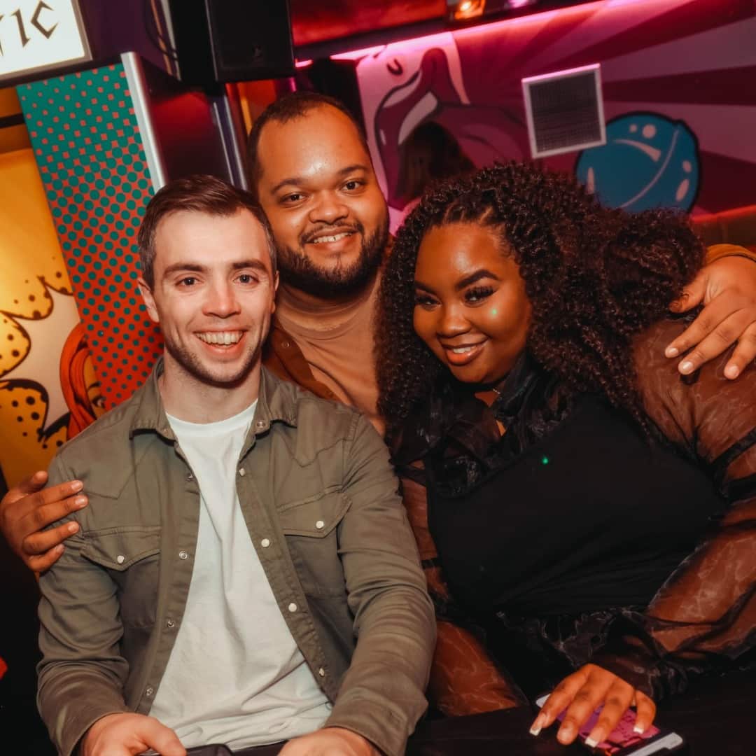 Three Popworld guests at the bar smiling at the camera