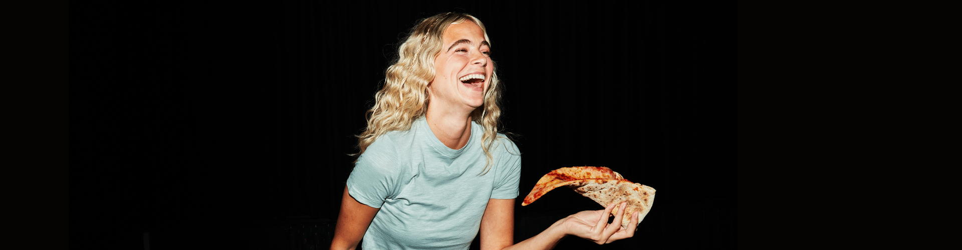 Person smiling at Rita's XXL pizza slice